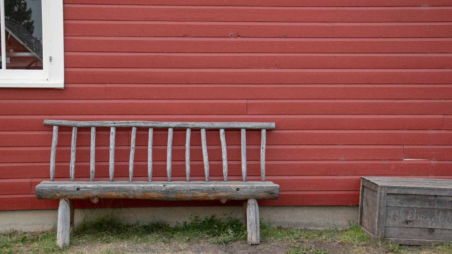 A house with autumn red siding and a wooden bench