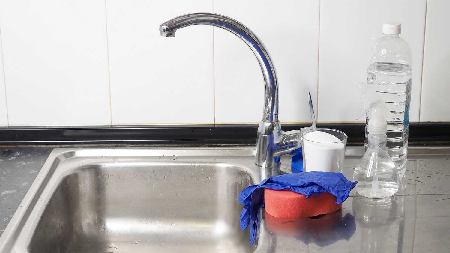 Containers with baking soda and vinegar sitting by the kitchen sink