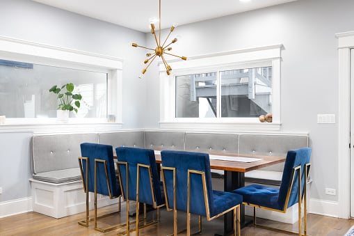 Modern corner dining room with blue chairs and a bench