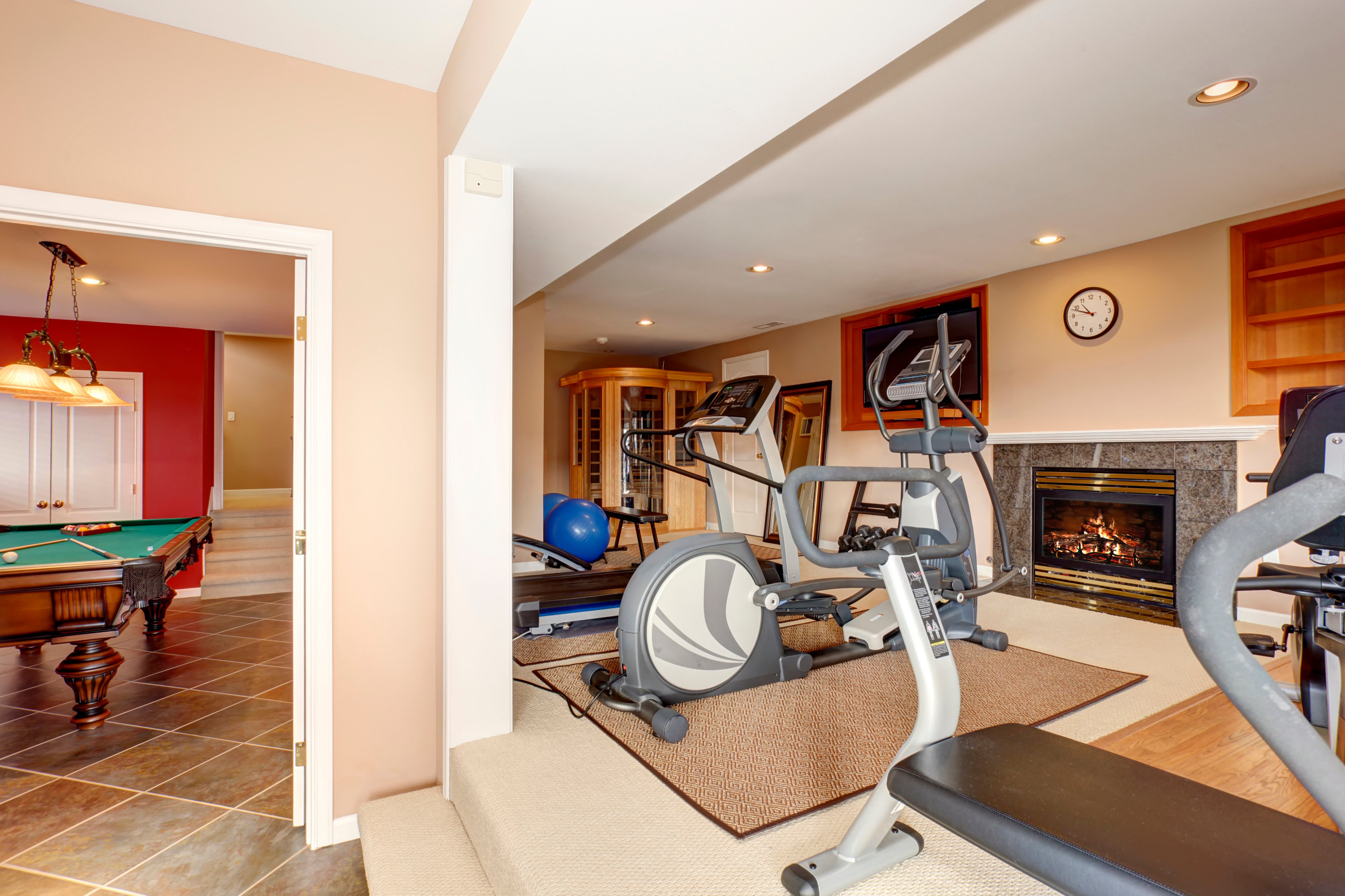 Basement home gym with gym equipment, a TV, pool table and fireplace