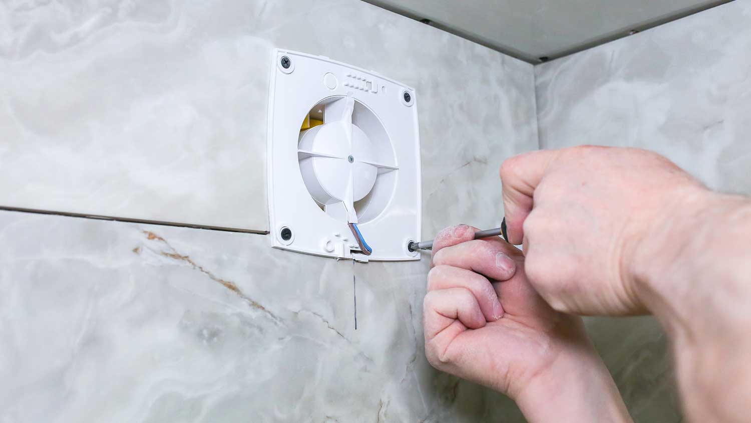A person repairing a bathroom fan