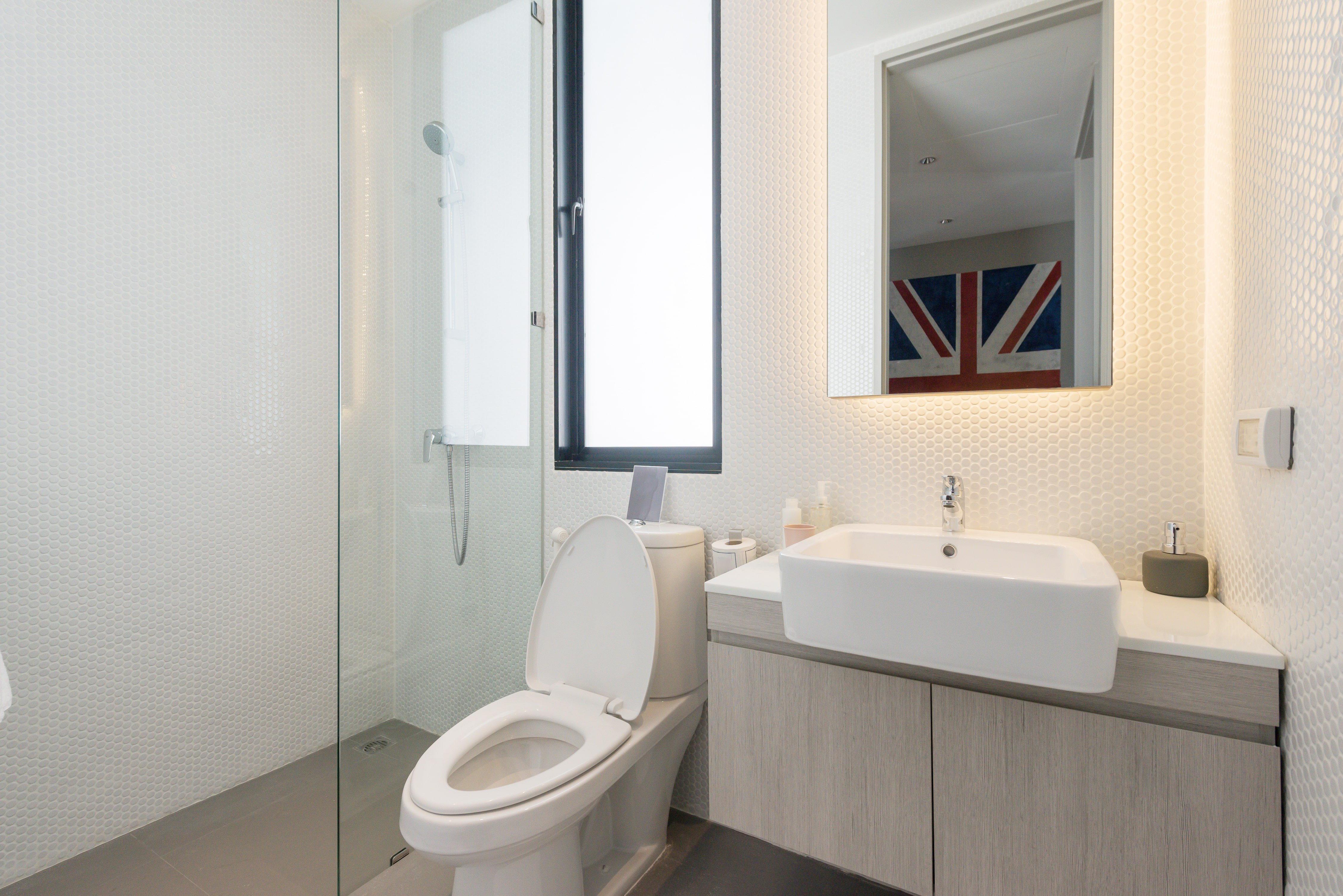 Small, modern bathroom with wooden vanity, vessel sink, and white penny tile backsplash