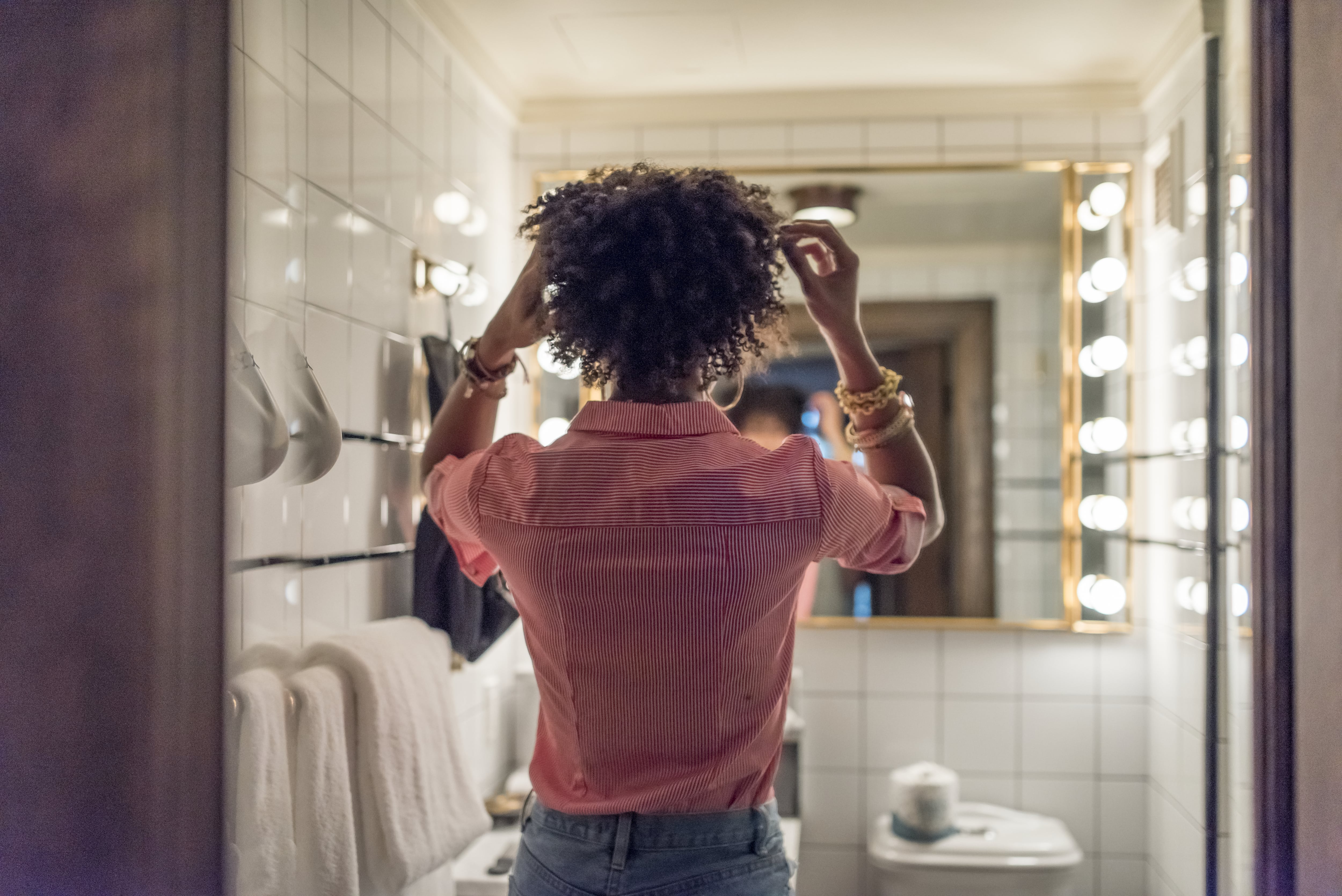 Woman getting ready in bathroom in front of Hollywood-style vanity mirror