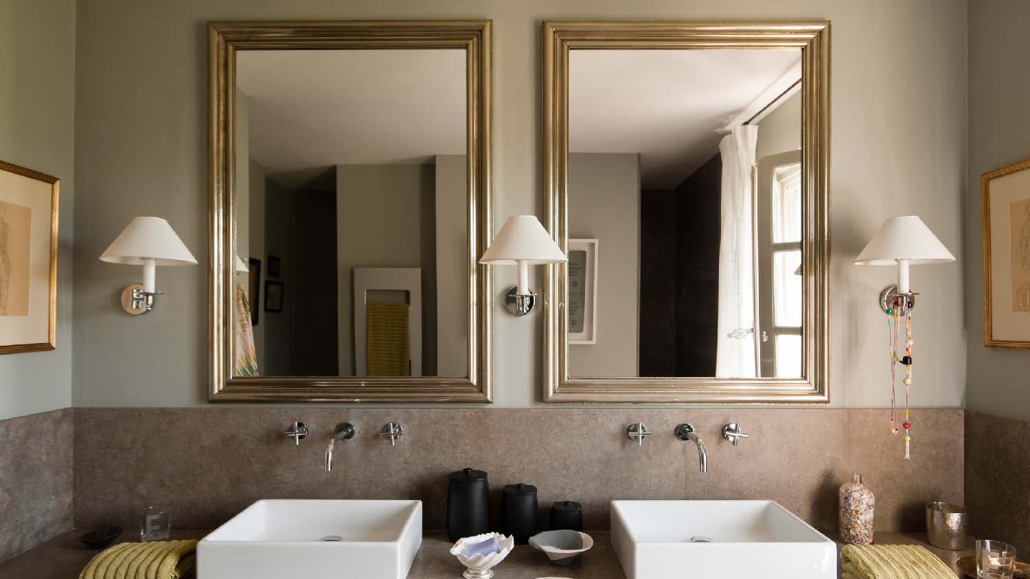 A bathroom with two sinks and sconces on the wall