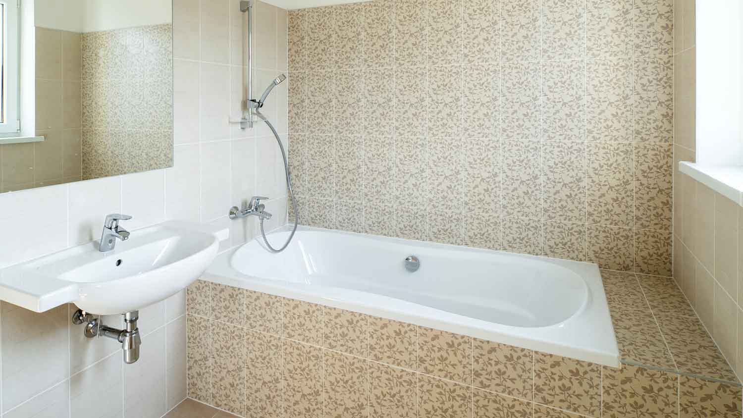 Bathroom with a fiberglass tub and beige tiles