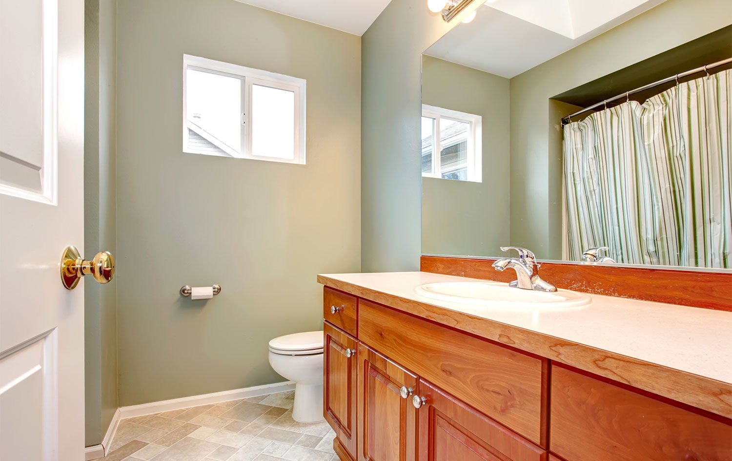 Bathroom with green walls and wooden cabinets