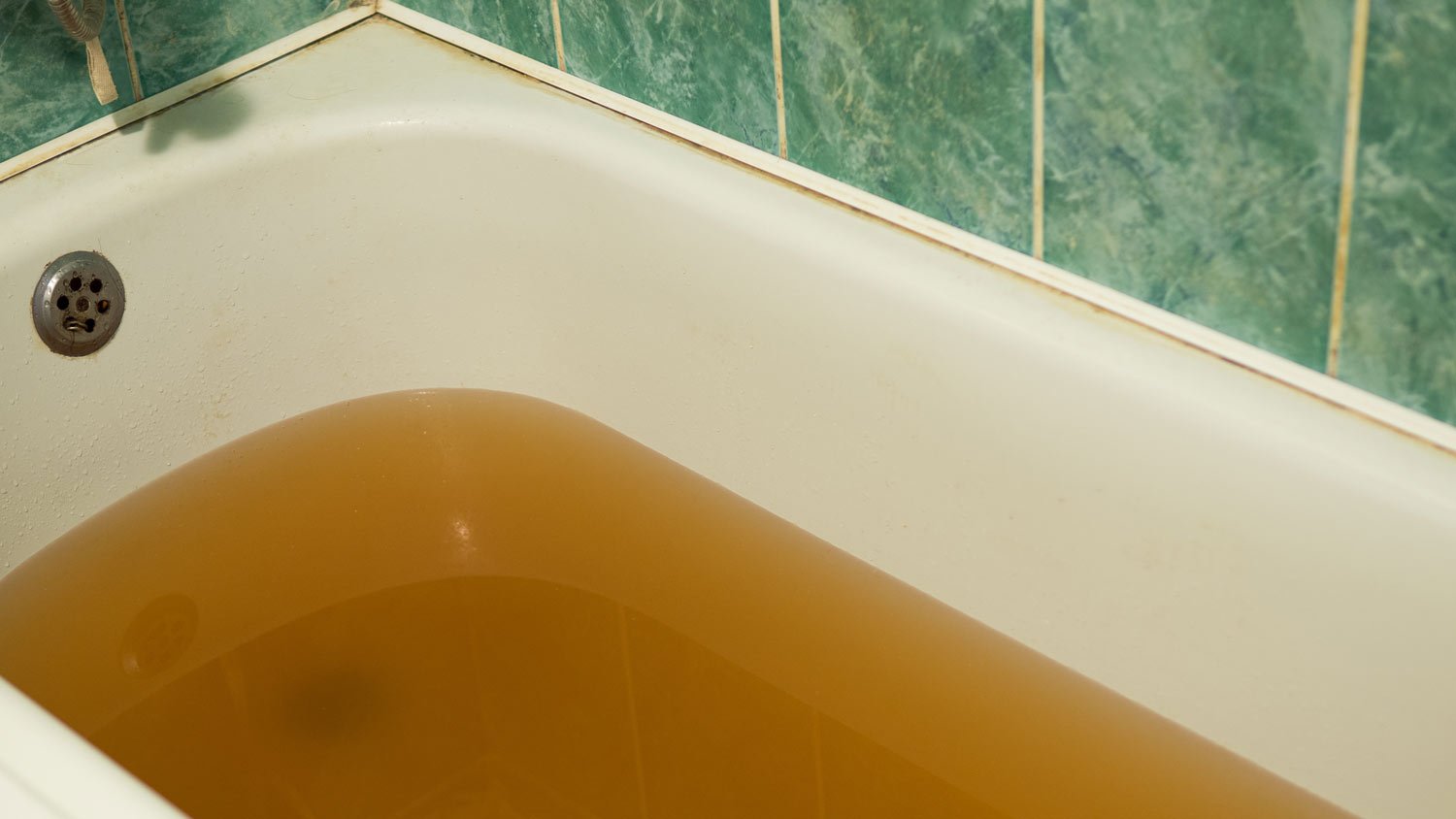 bathtub filled with rusty yellow water