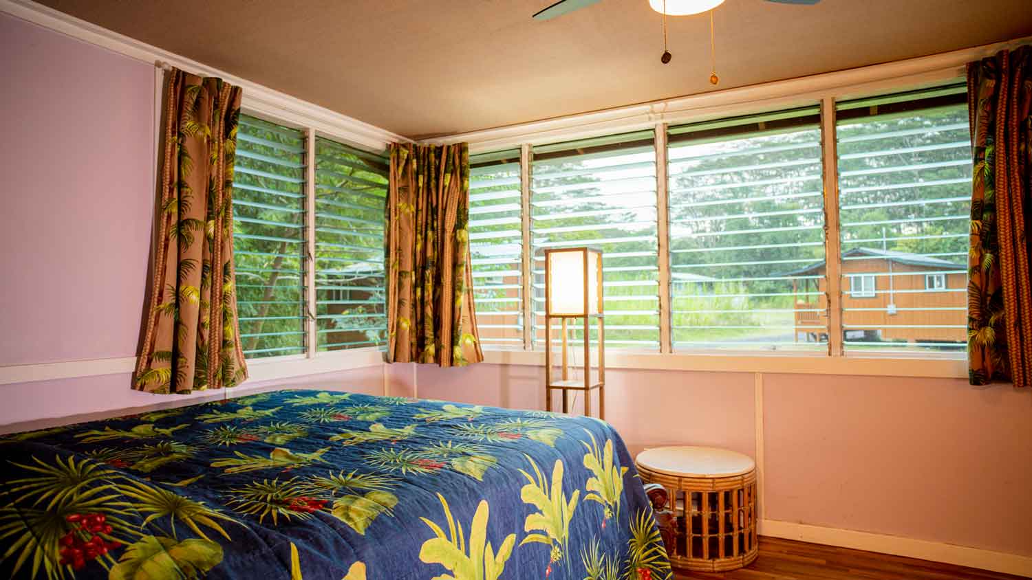 A bedroom with a ceiling fan and jalousie windows