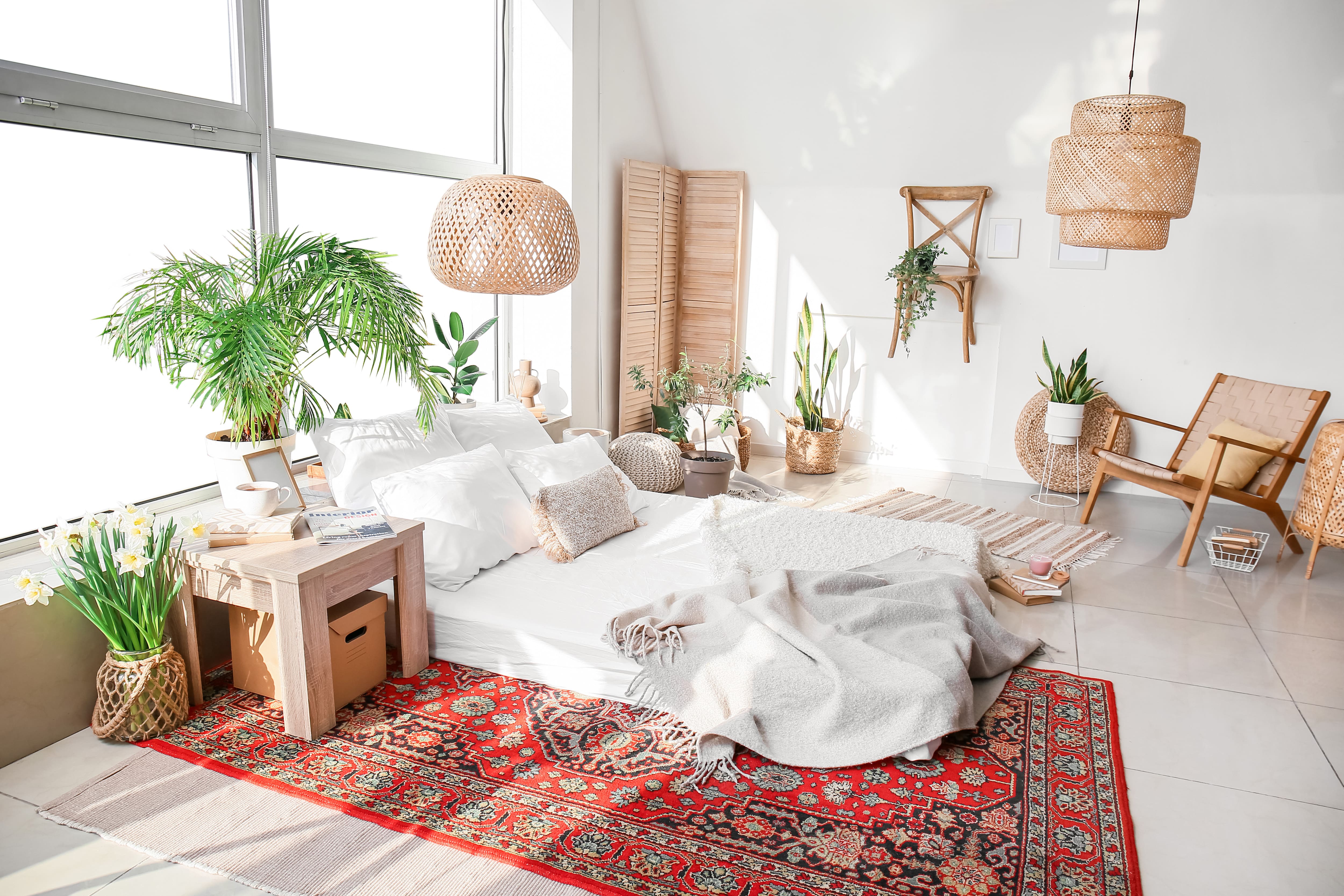 Beautiful boho bedroom with rattan light fixtures, a wooden nightstand, and mix and match rugs