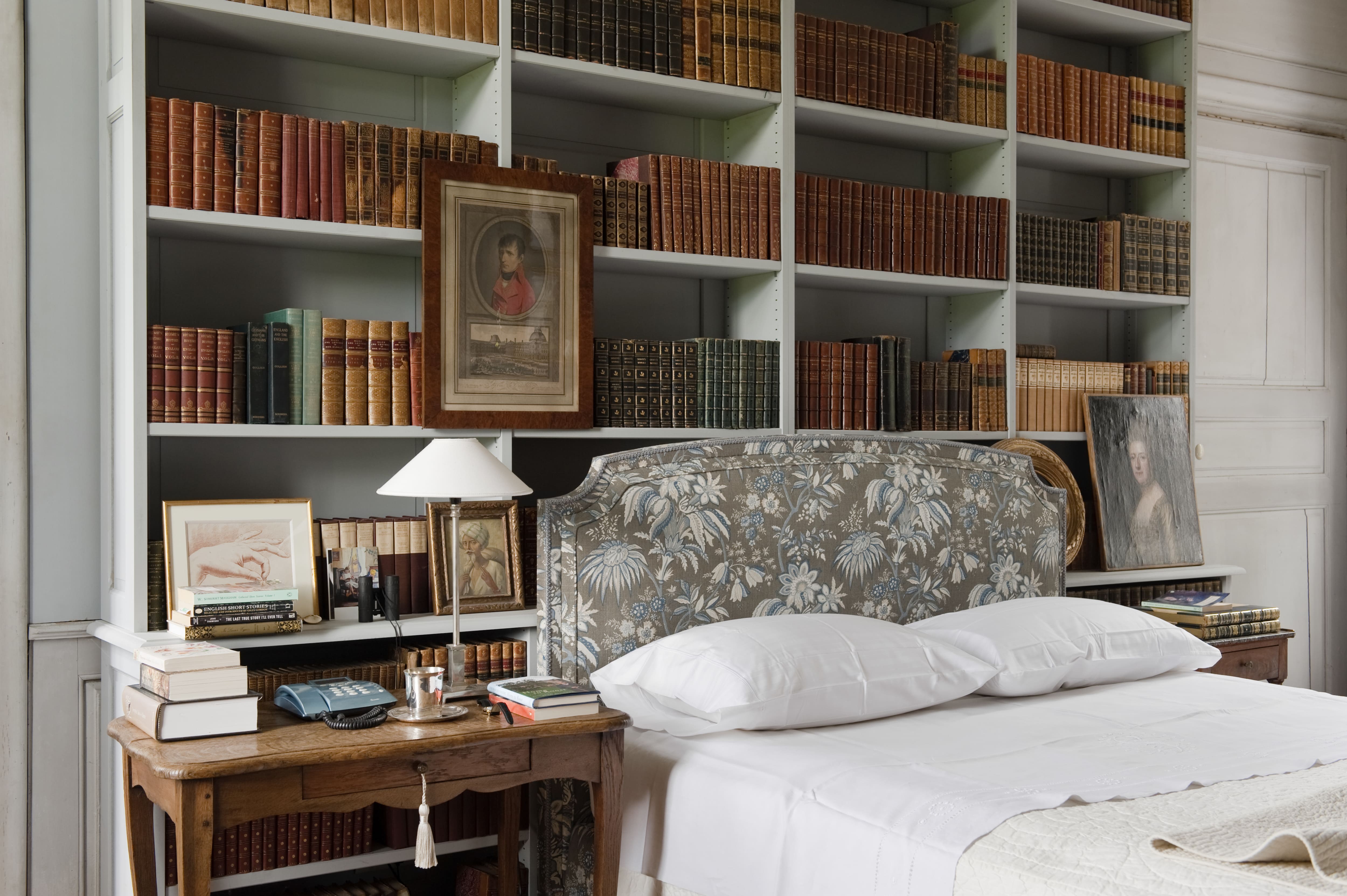 Warm bedroom with cozy bed and built-in shelves full of books