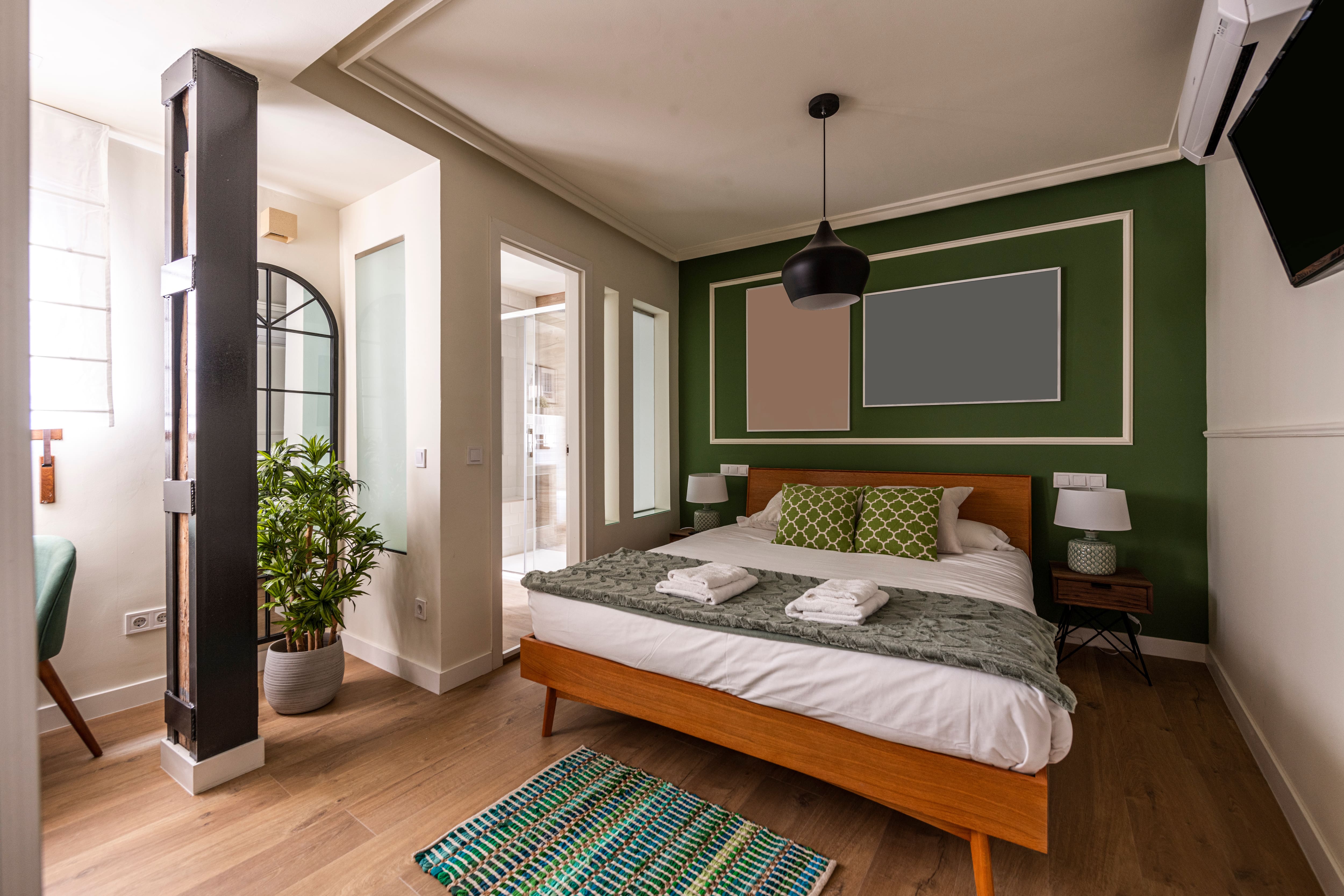 Bedroom with wooden bedframe, windows, coffered ceilings, and a green accent wall