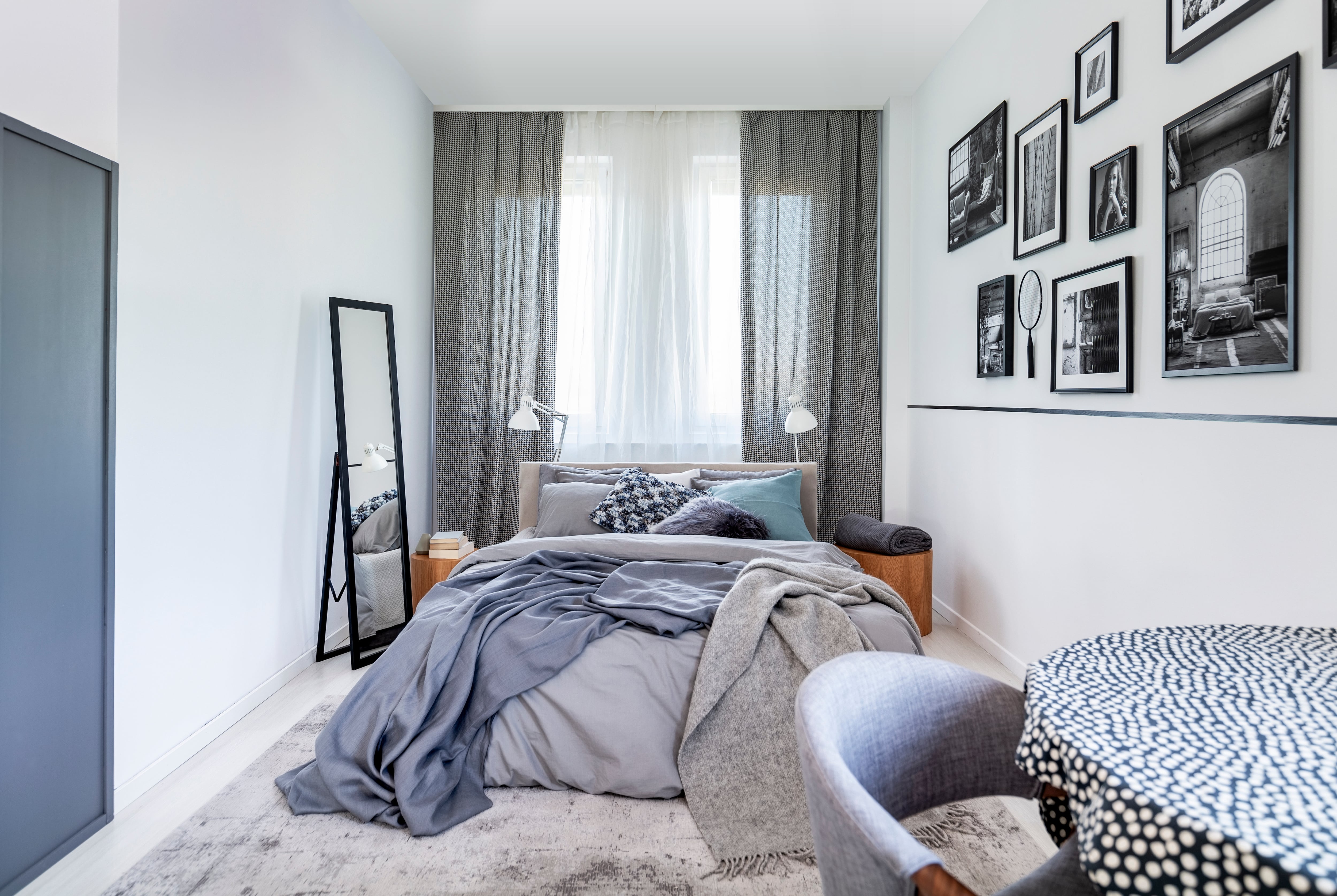 Modern bedroom with window, gray bed, and framed photographs on wall