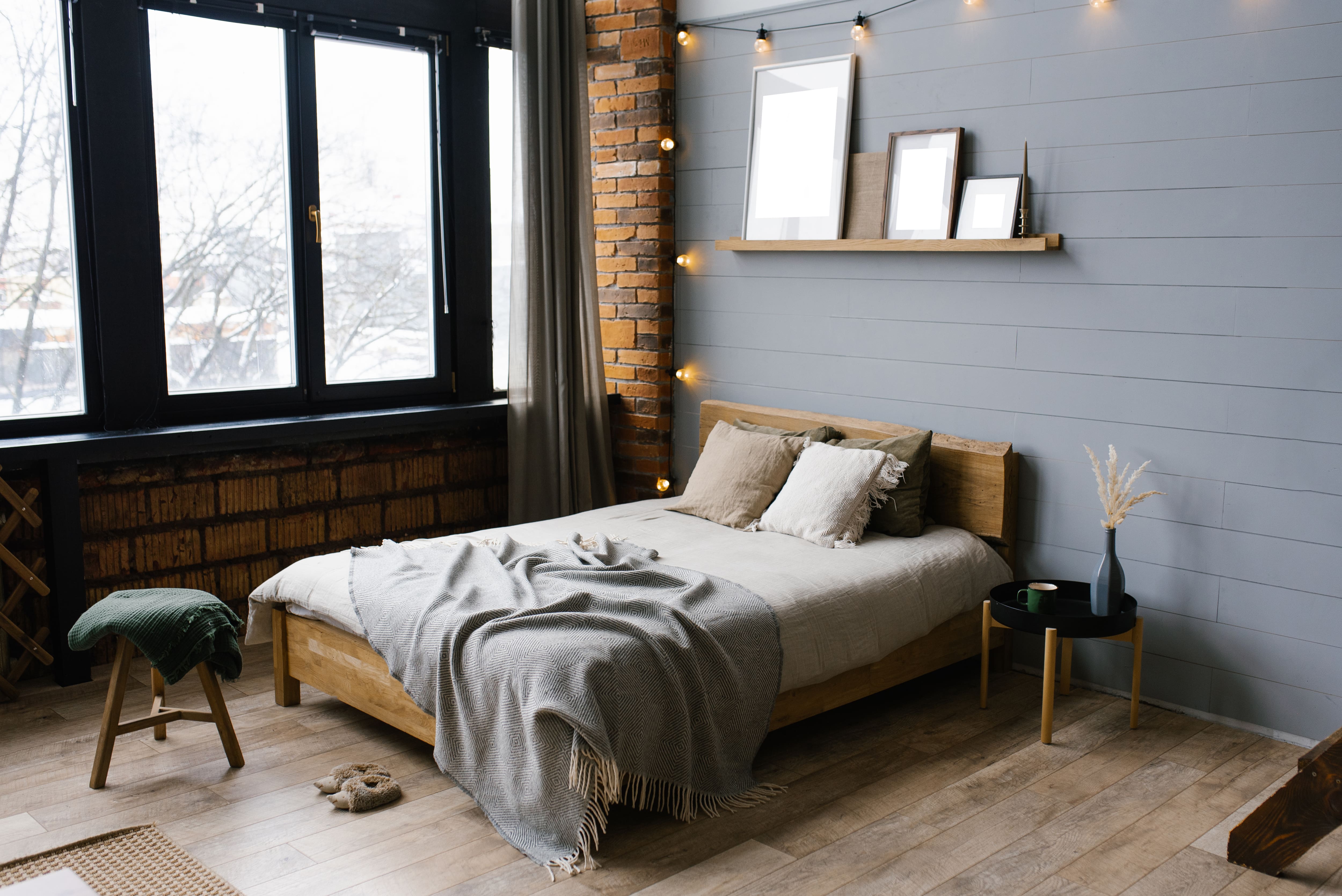 Modern bedroom with exposed brick wall, gray shiplap wall, and wood floors