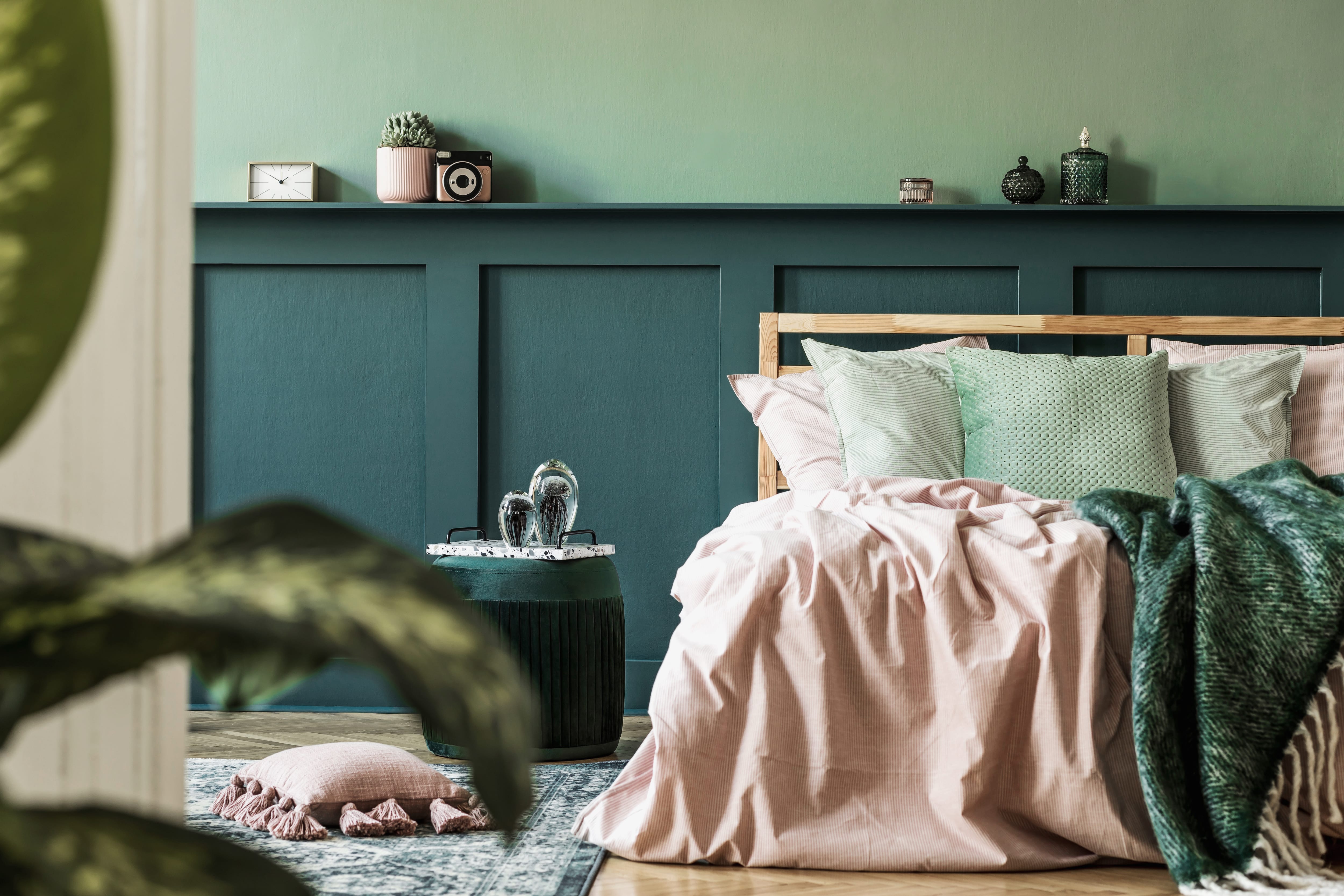 Stylish bedroom with cozy bed, throw pillows, and two-toned green walls