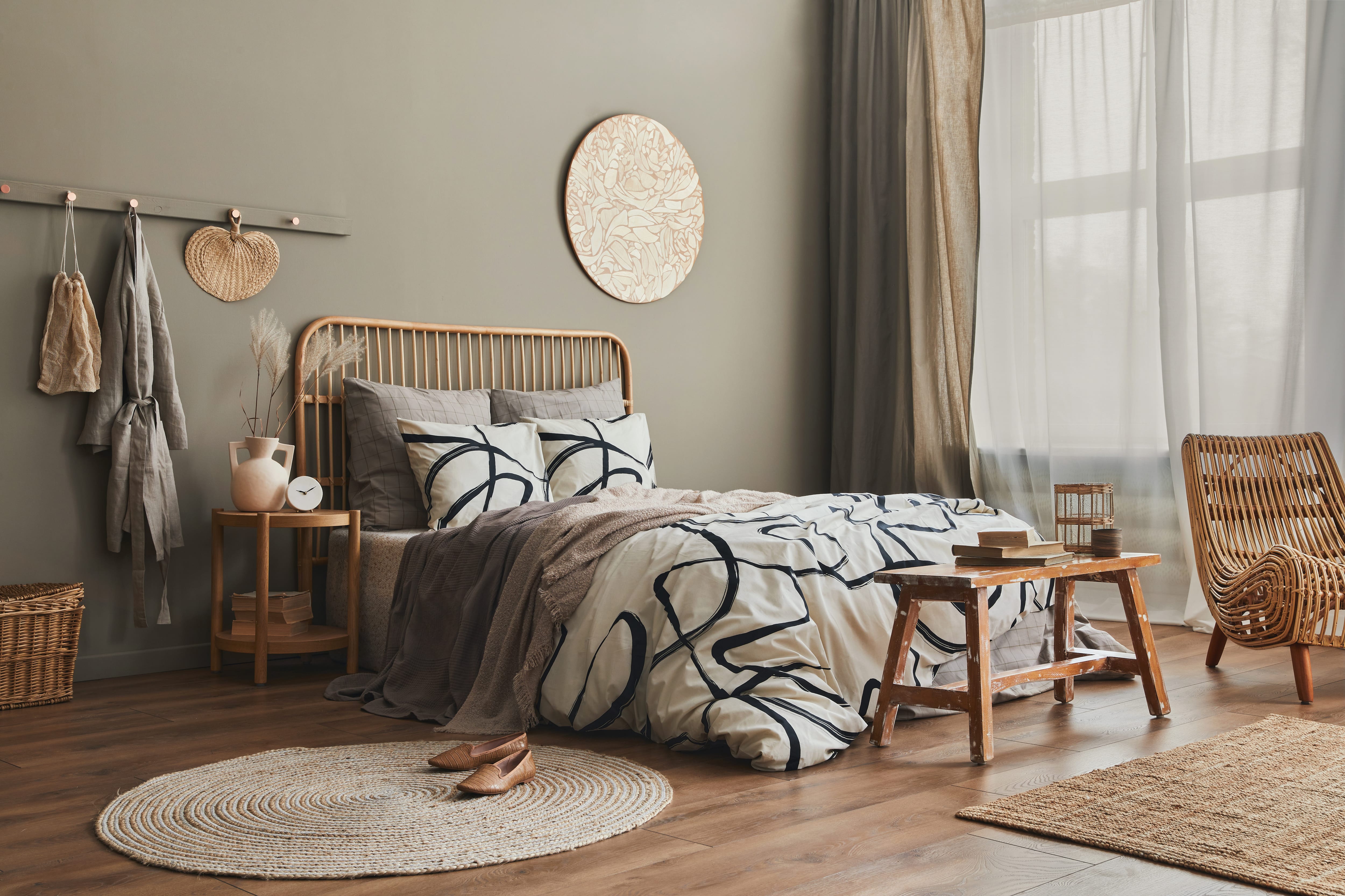 Warm, modern bedroom with two jute rugs, a rattan headboard, and a wooden bench