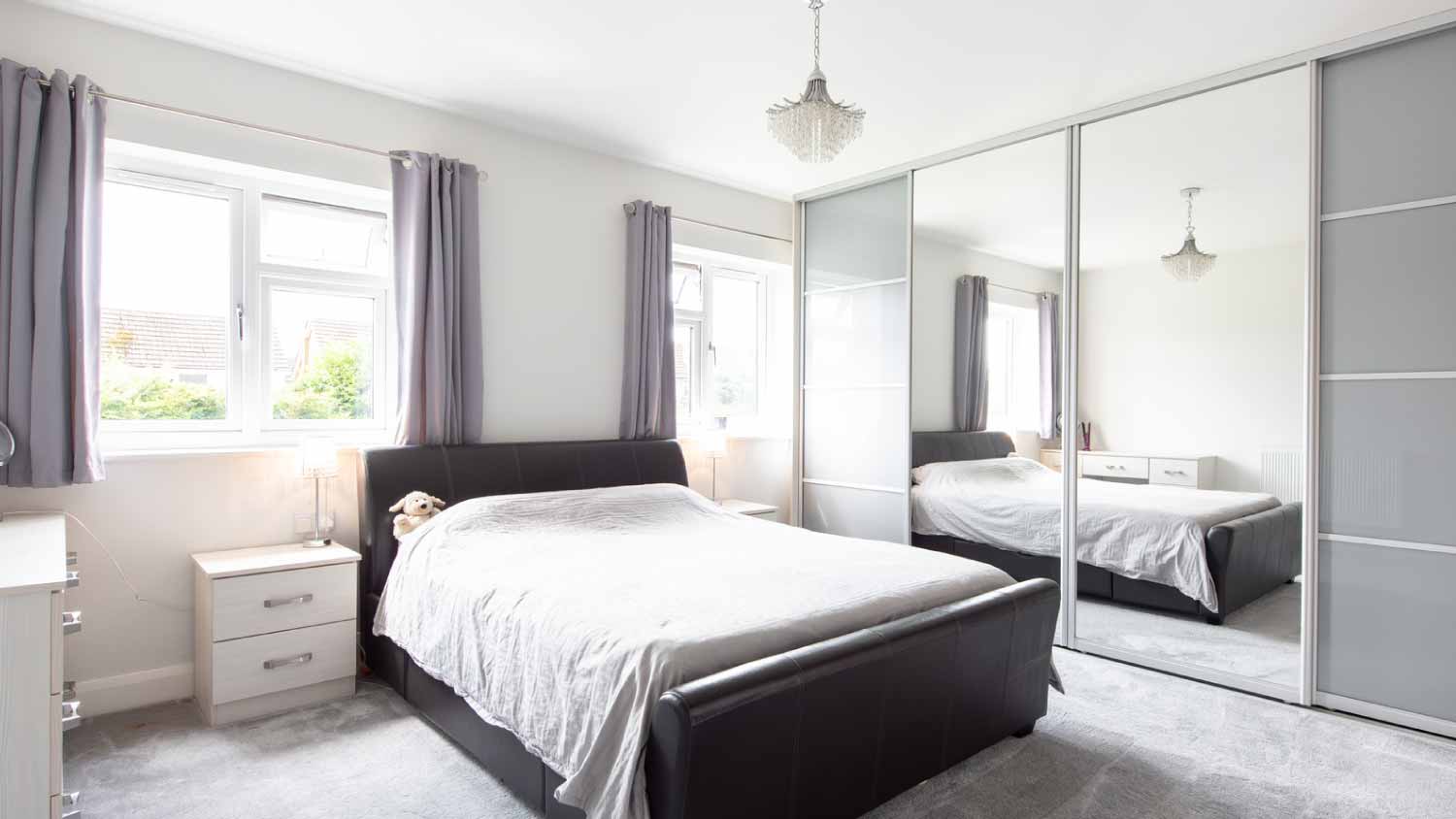 A bedroom with sliding mirrored doors wardrobe