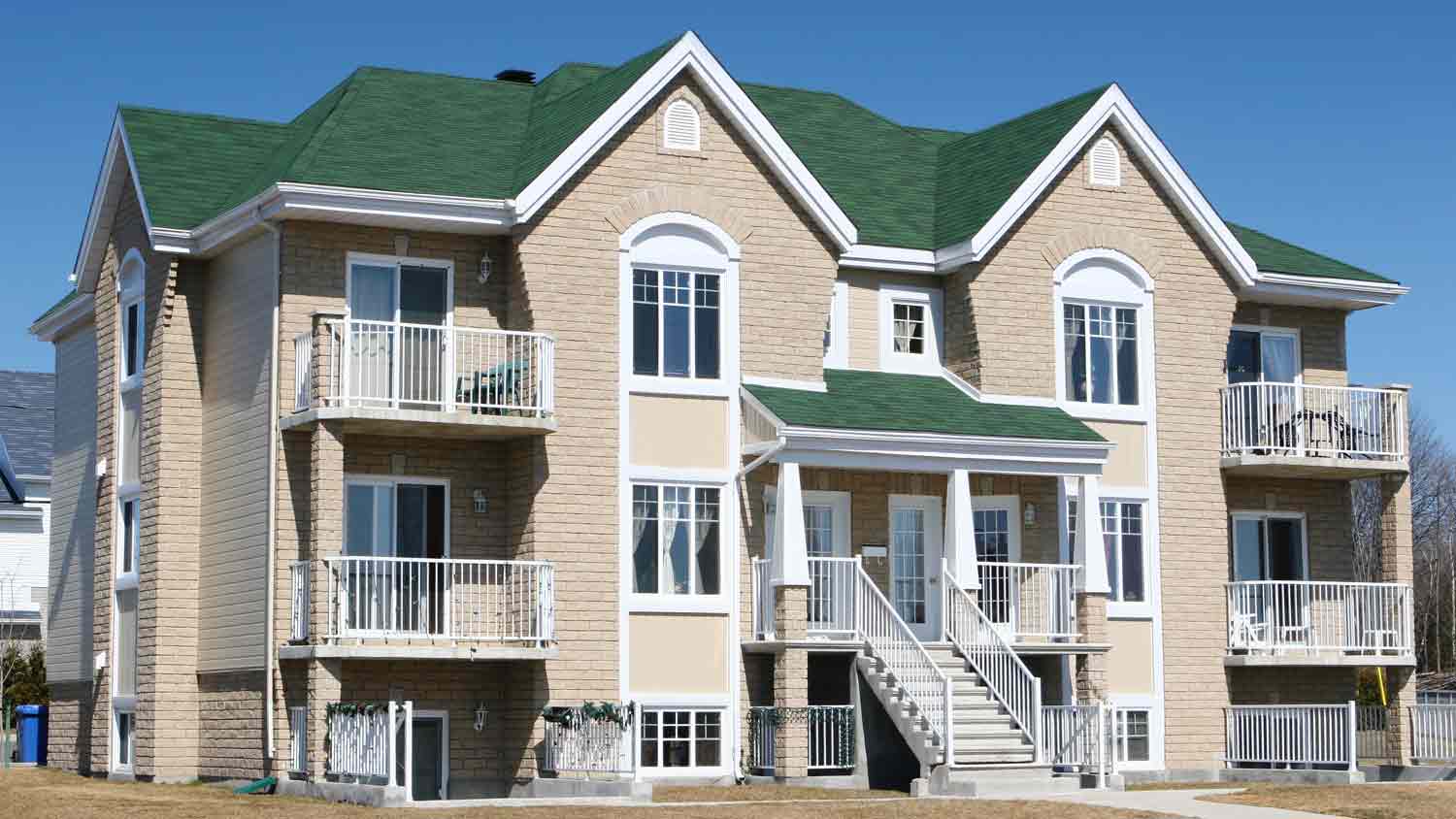 large beige home with green roof