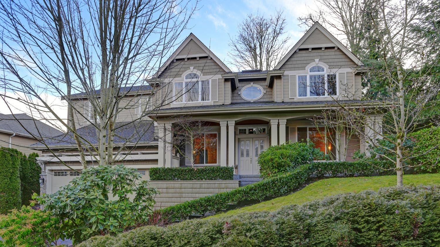 A gorgeous gray and green craftsman house with a lush landscaped garden