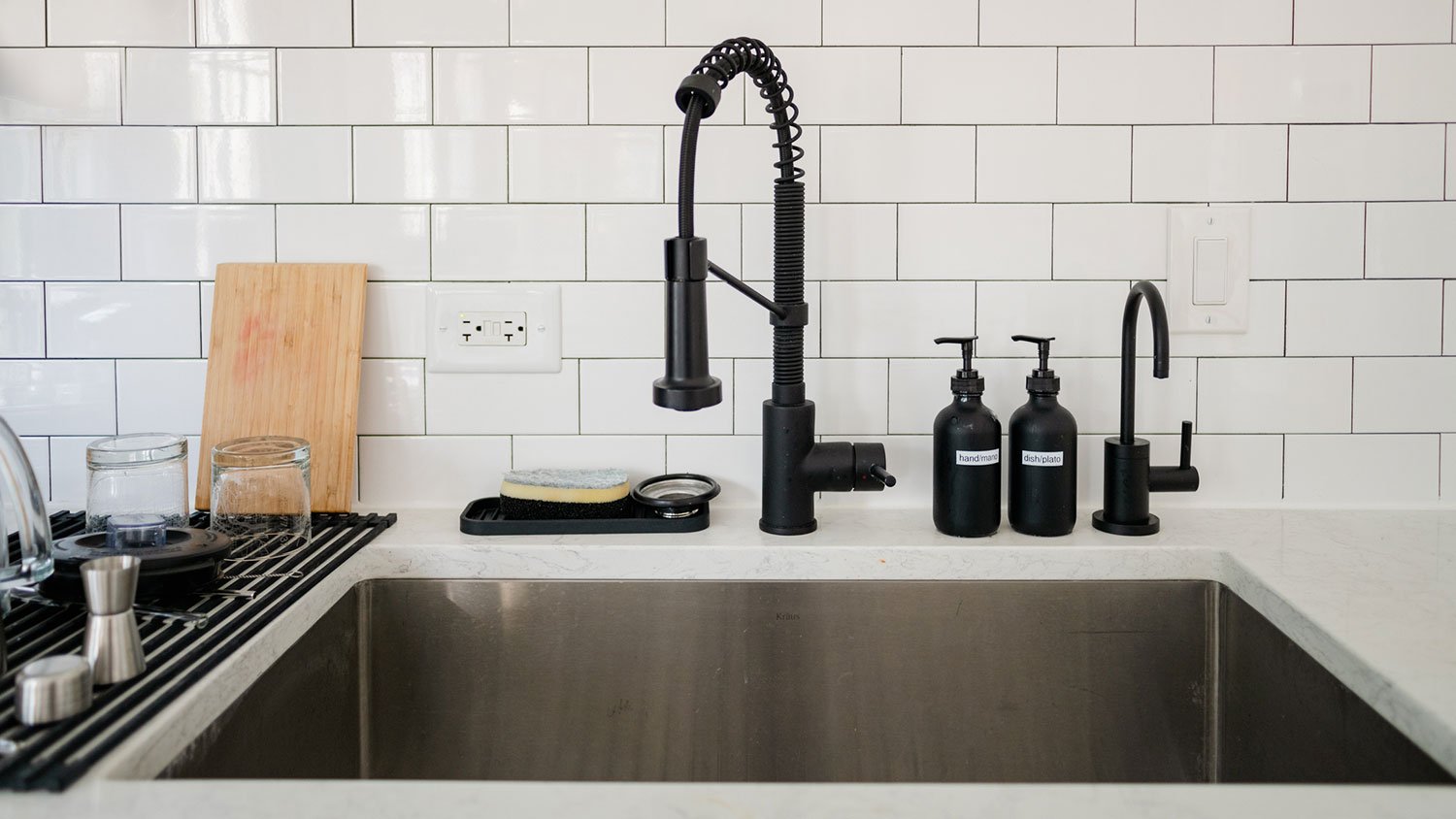 Kitchen sink with black faucet and white tiles