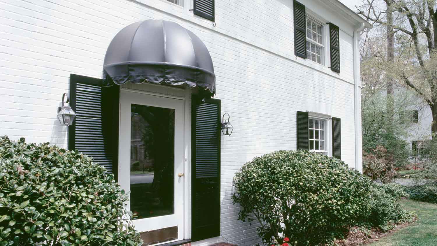 Door awning installed on a black and white house exterior