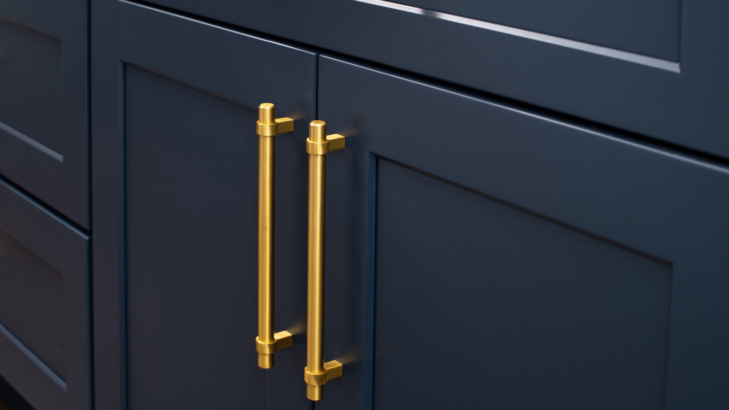 A blue kitchen cabinet with a gold handle