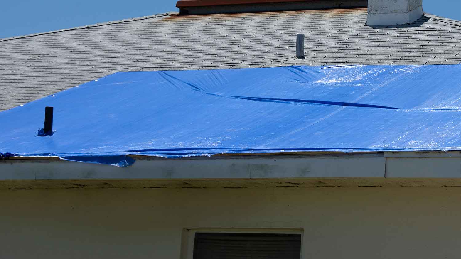 A view of a roof with a blue tarp on it