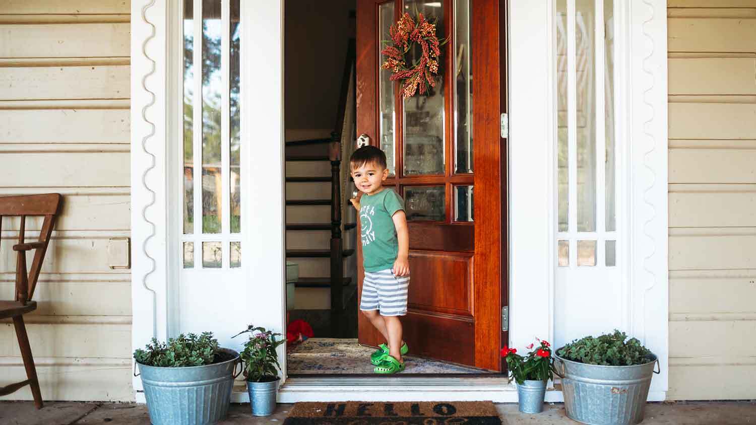 Young boy closing fiberglass entry door