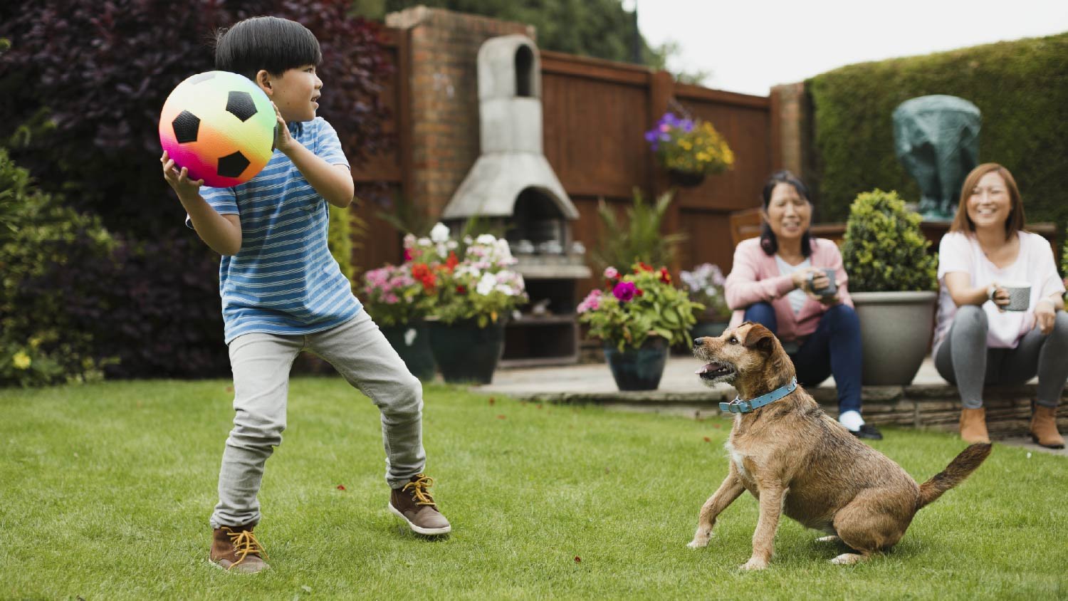 Boy playing fetch in the garden 