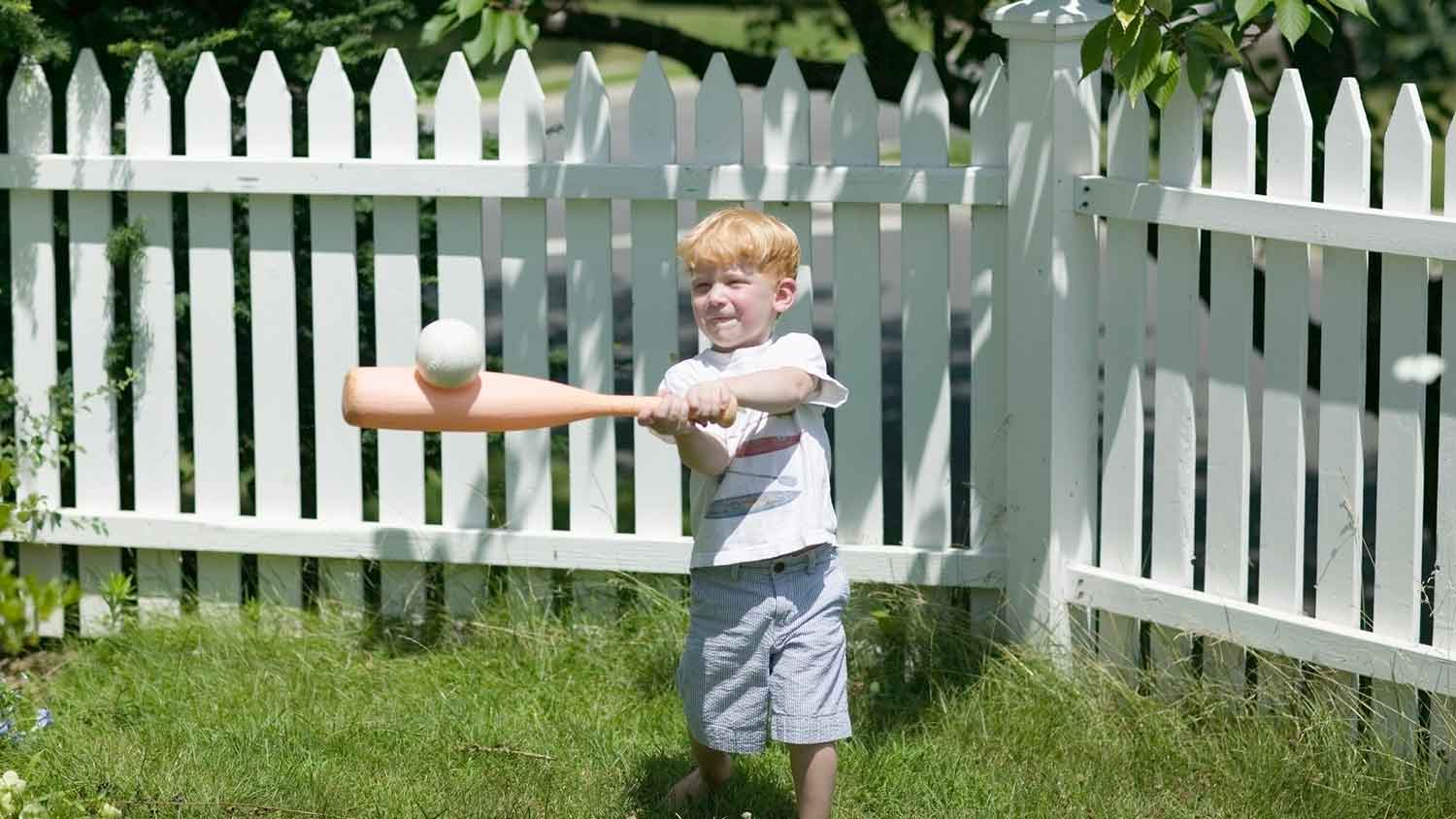 Small boy playing baseball in the yard