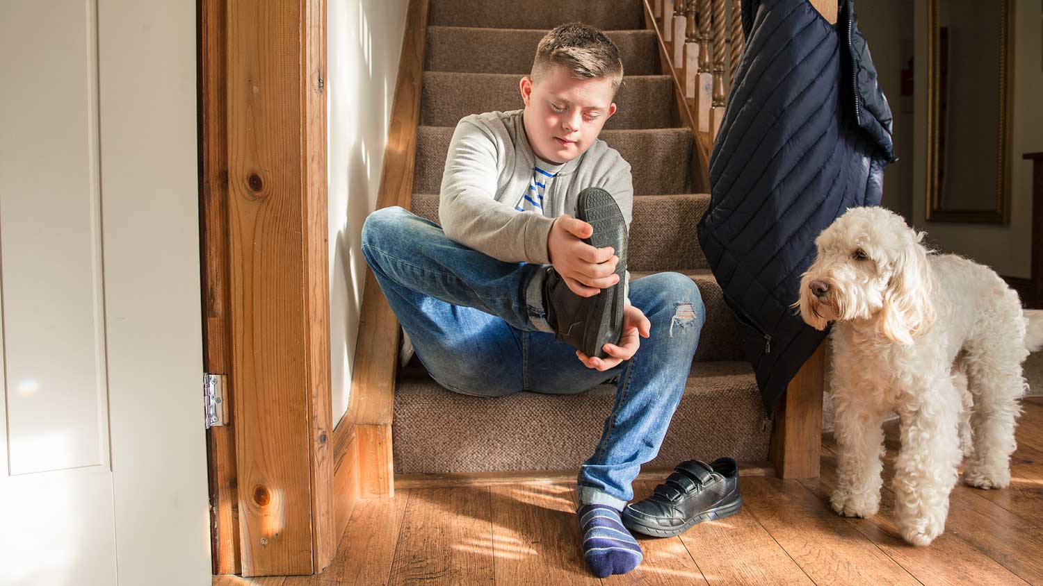 Boy sitting on the stairway taking his shoes off