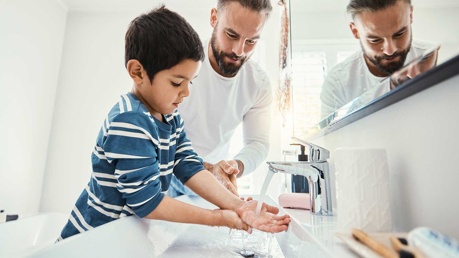 Father helping son wash hands in the bathroom