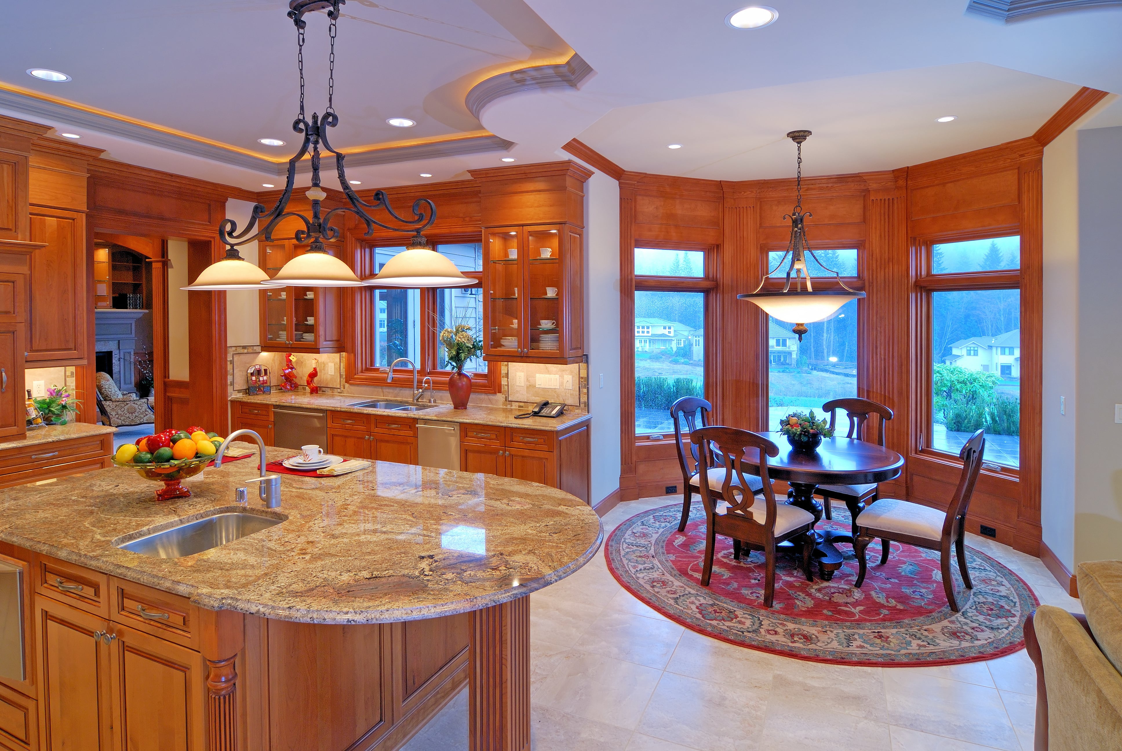 A wooden round table in a breakfast nook with a red round area rug underneath