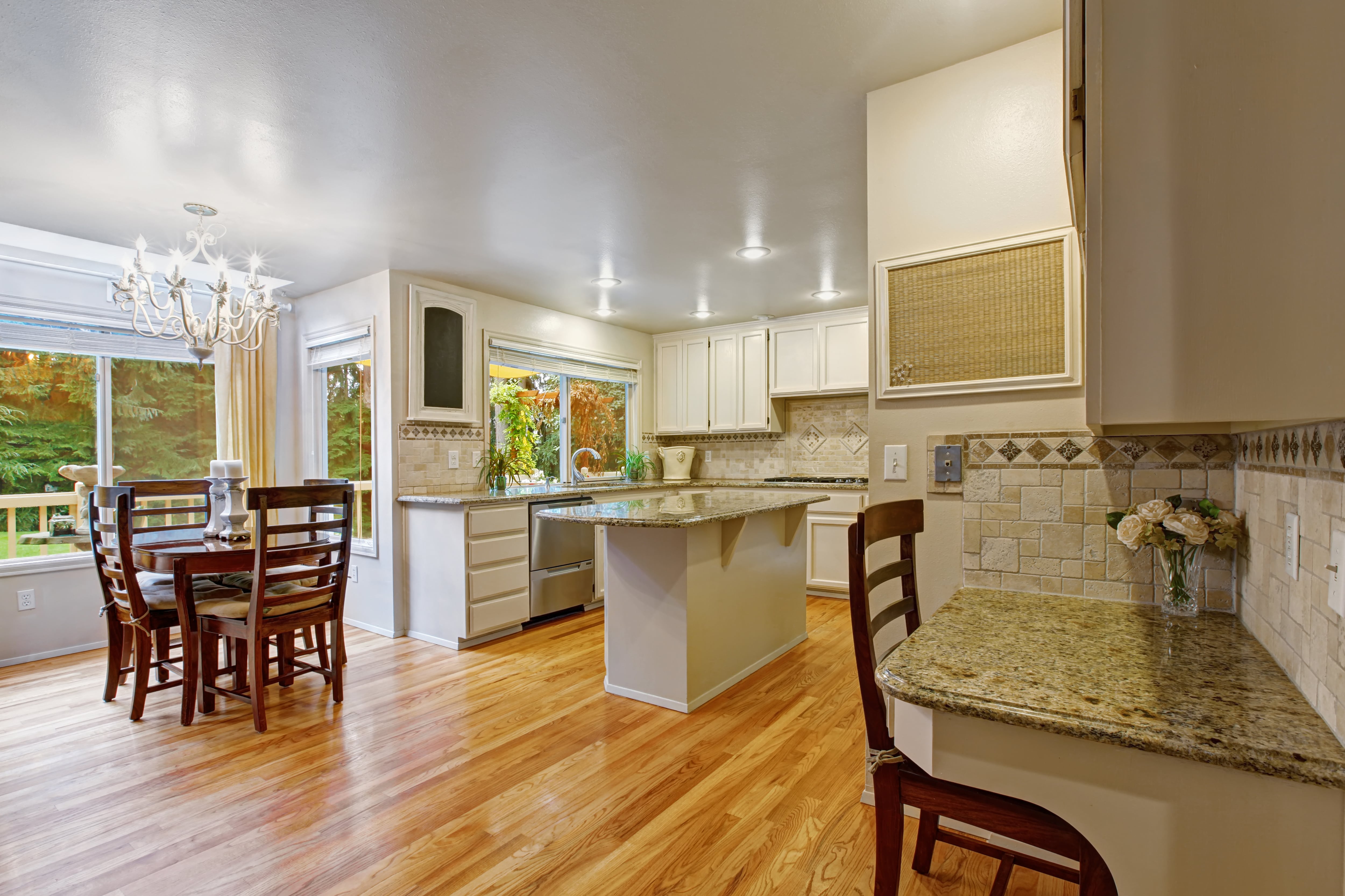 An open concept kitchen with a chandelier above a small round kitchen table