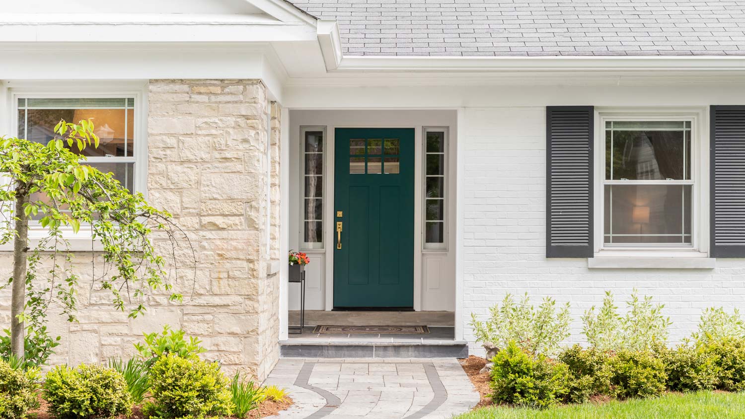 White brick and stone exterior front of house with black shutters
