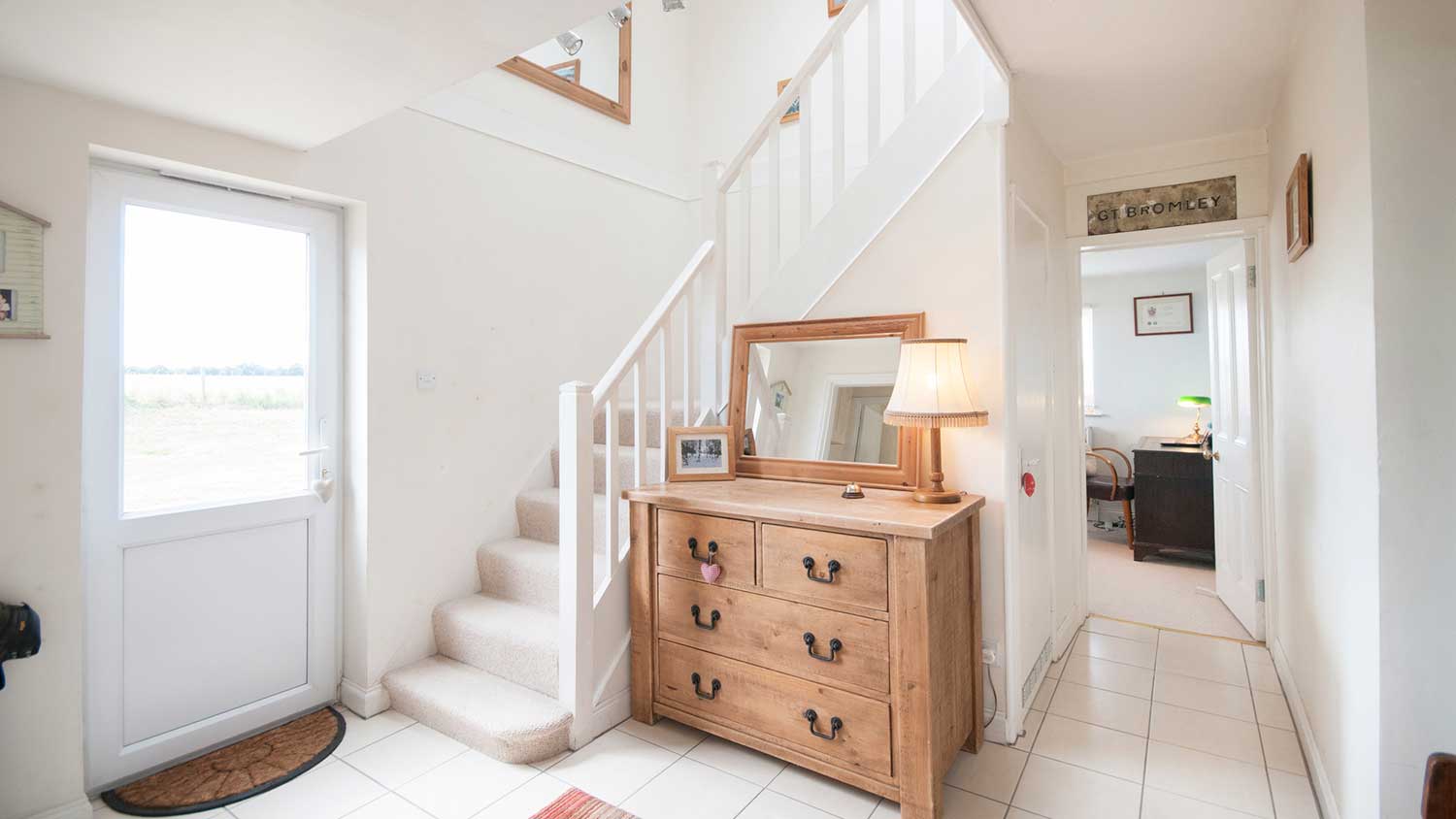 Bright home entryway with white walls and wooden furniture