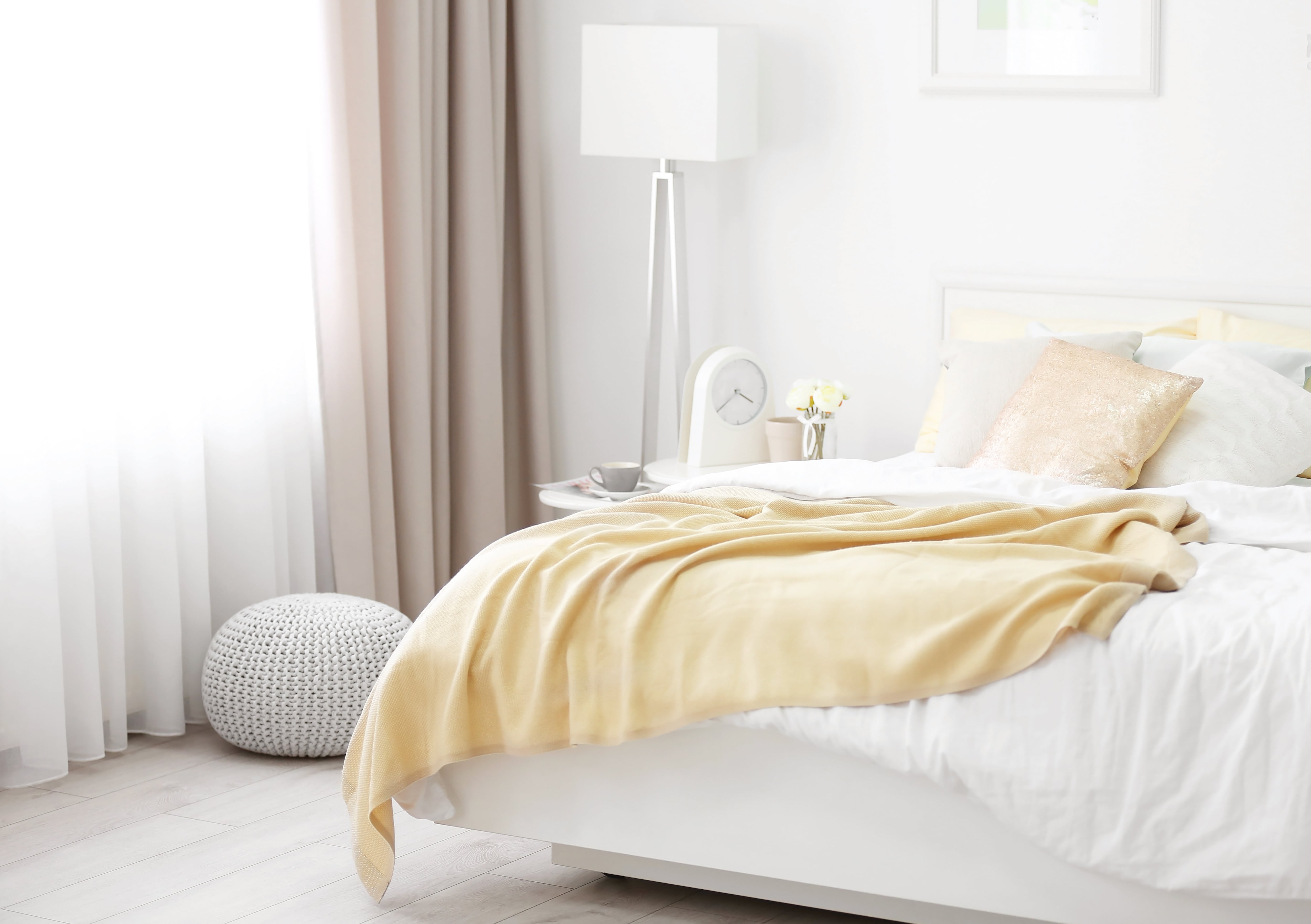 A light bedroom with bright white walls and white bedding