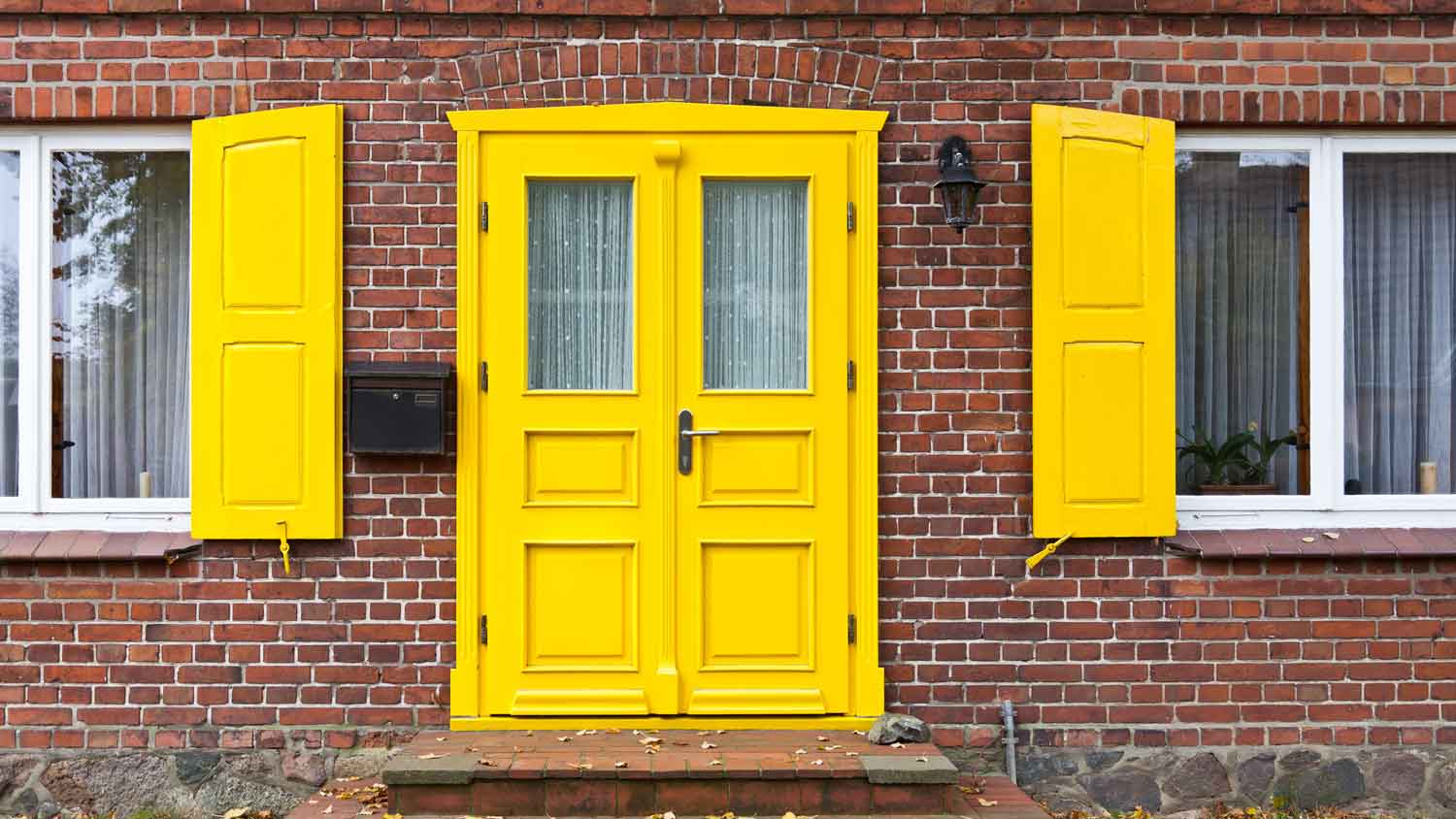 A bright yellow front door in a brick house