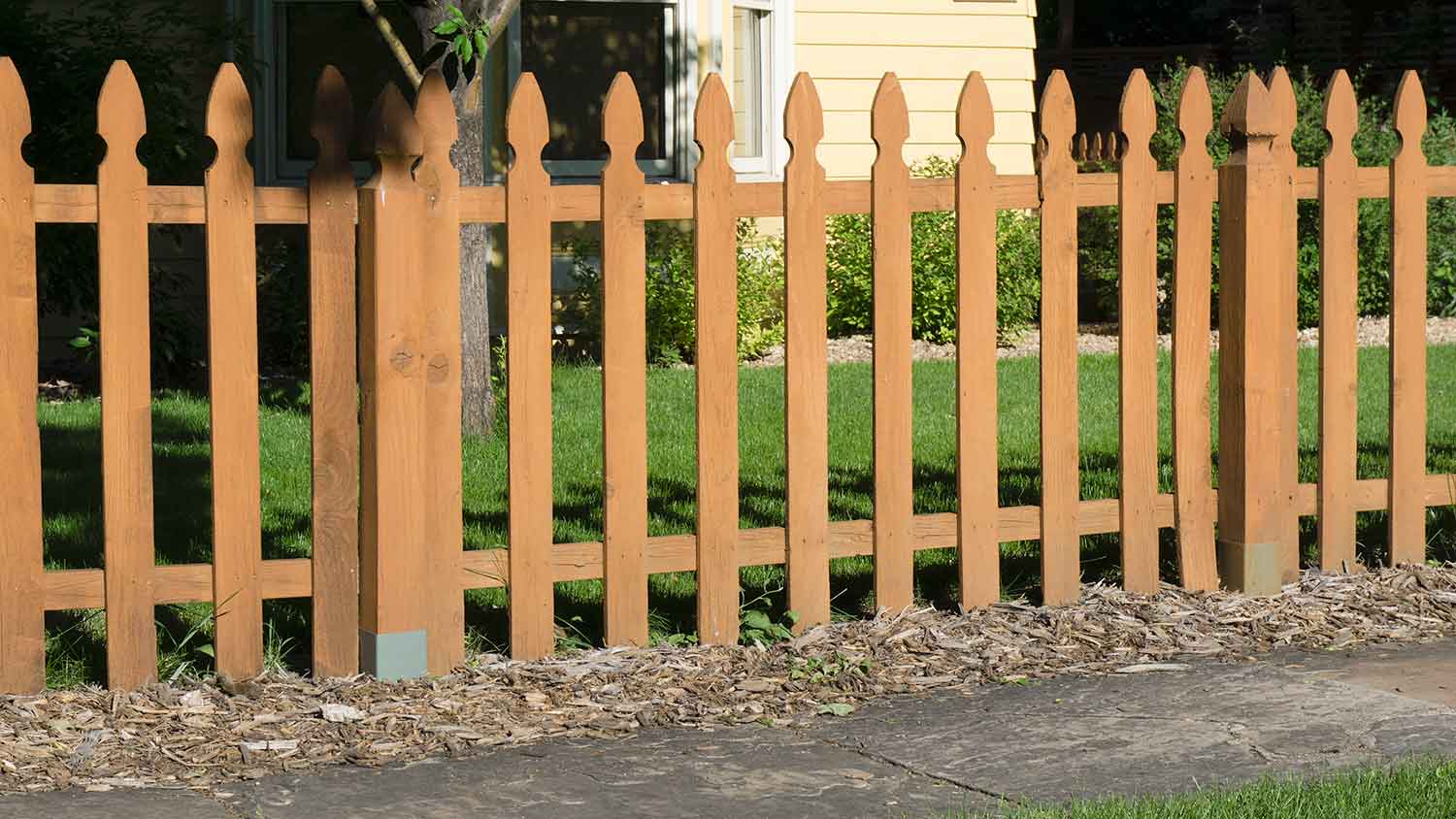 Wooden picket fence installed in a front yard