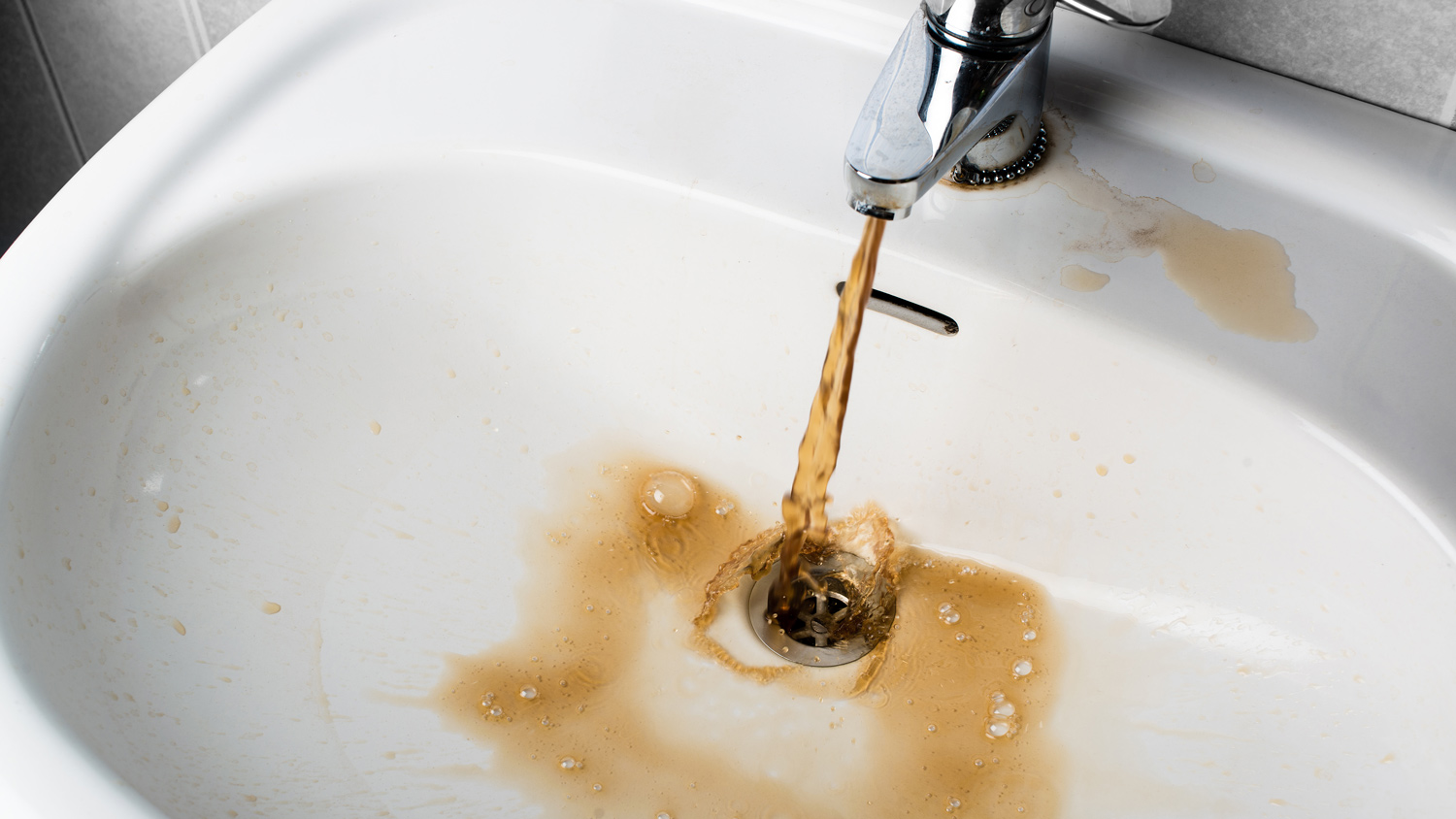 Close-up of young man washing a glass in sink at home