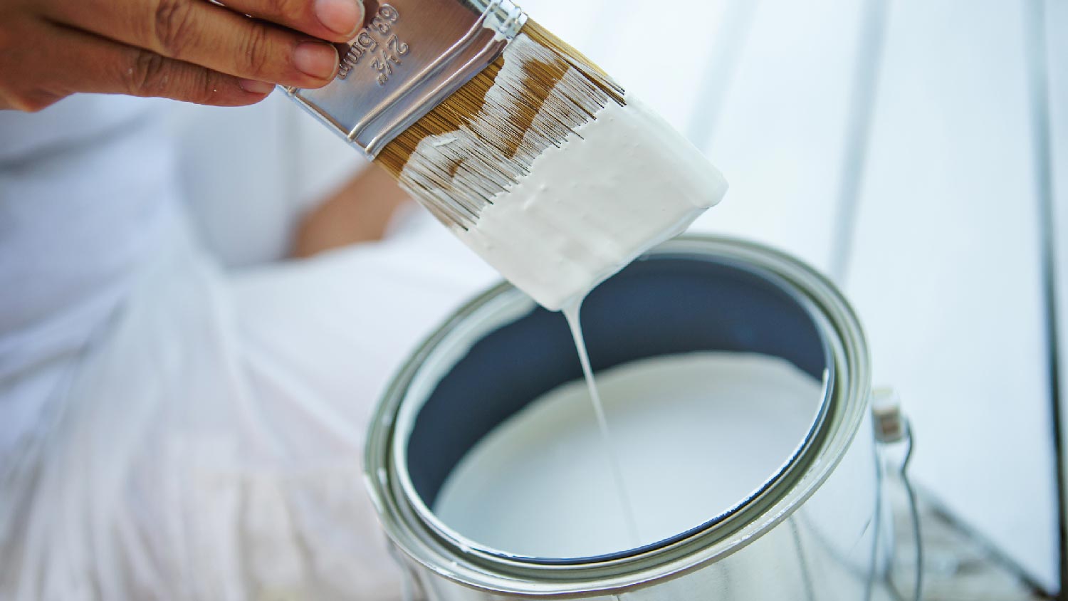 Close-up of a brush and a bucket filled with paint