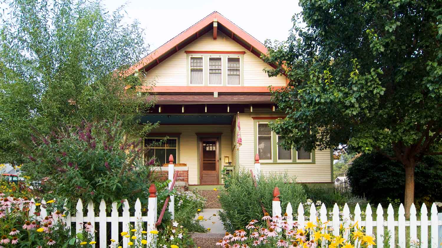 A bungalow with a gable roof and a lush garden