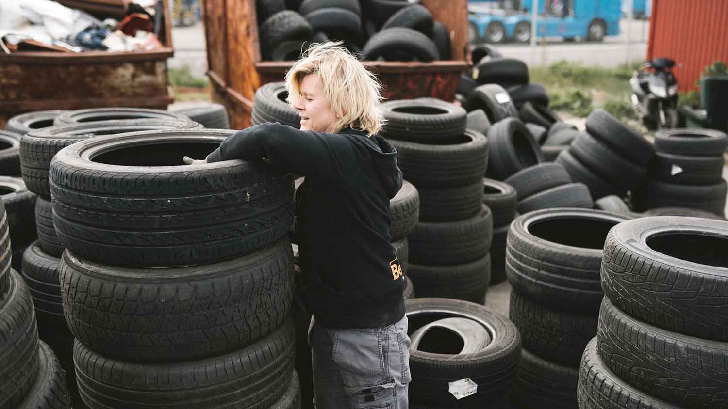 Person stacking car tires in a recycling facility