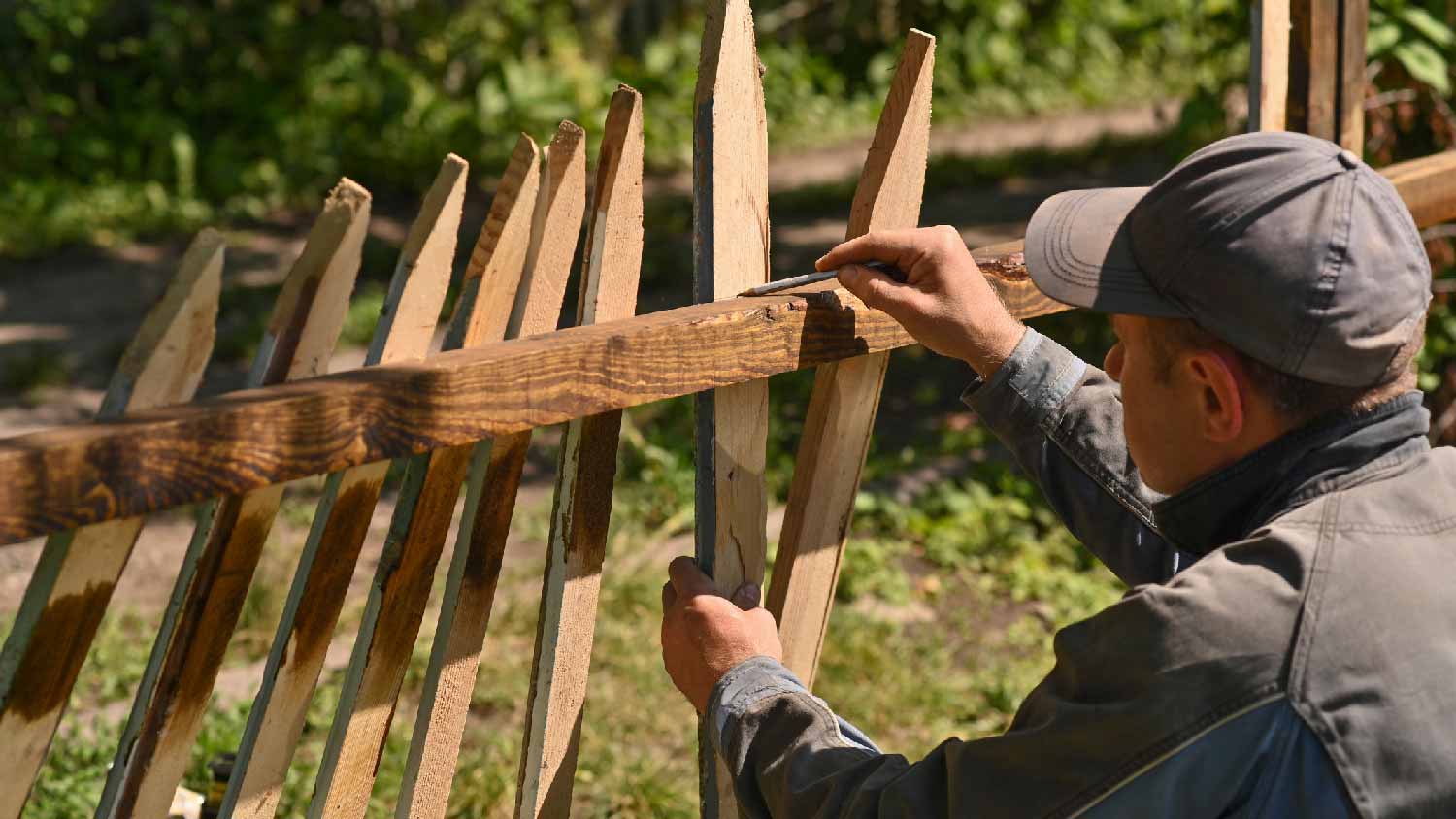 A carpenter building a wooden fence