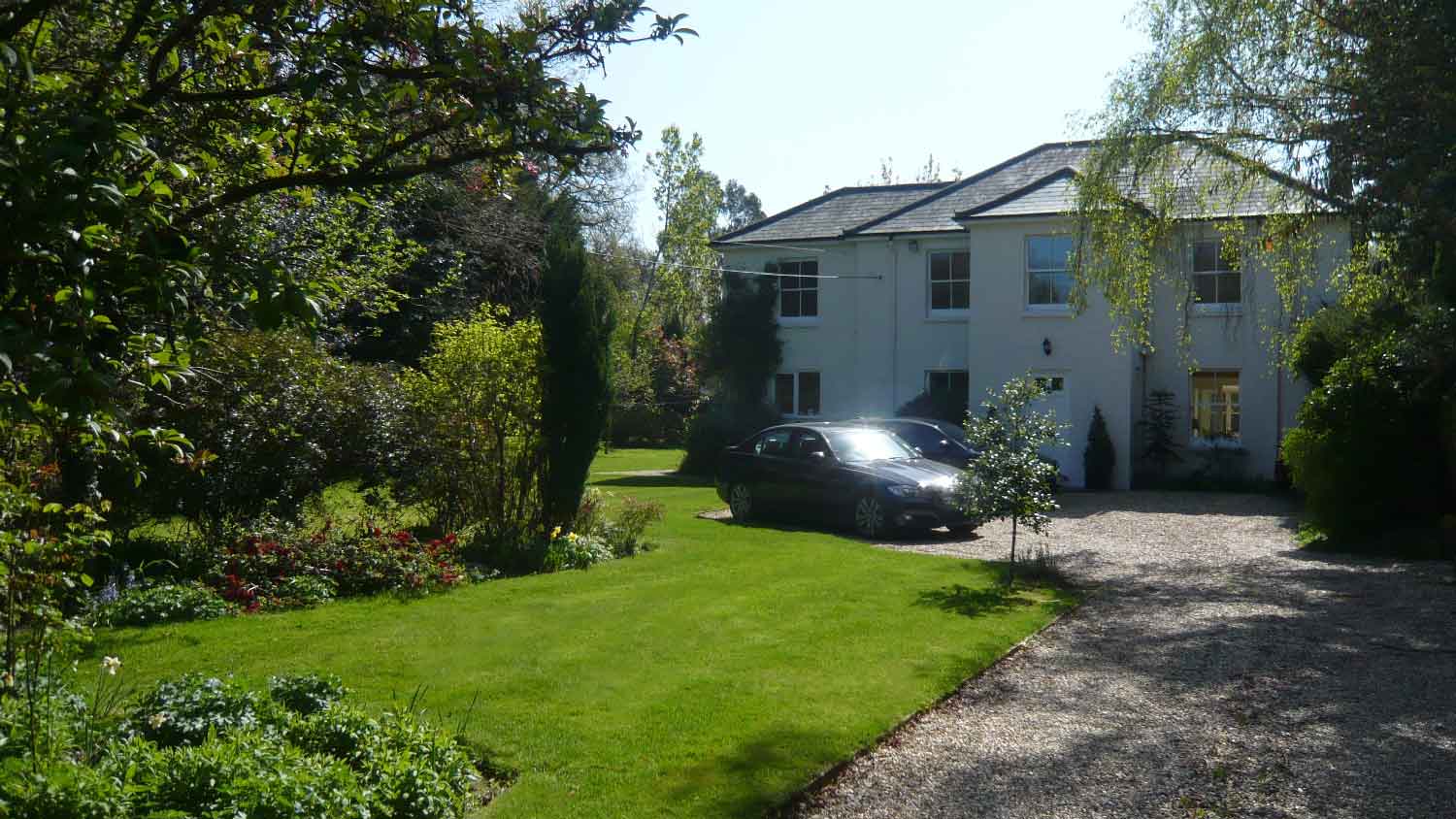 Two cars parked on a gravel driveway in front of a house