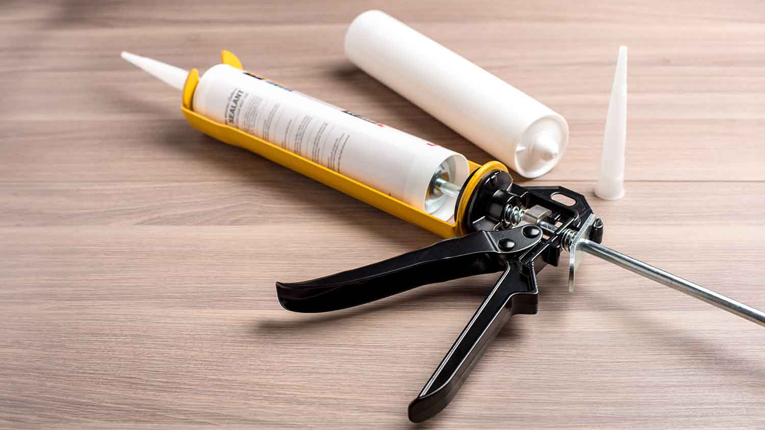  A caulk gun on a wooden floor