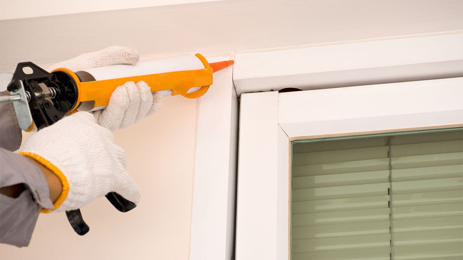 A view of someone caulking an exterior window