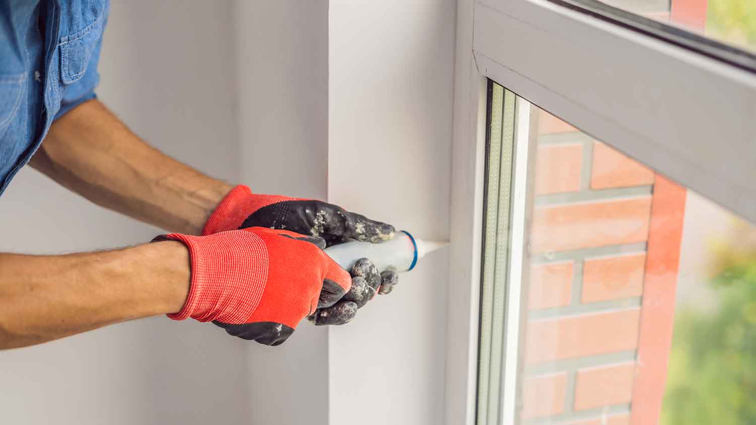 Worker caulking window to prevent leaks 