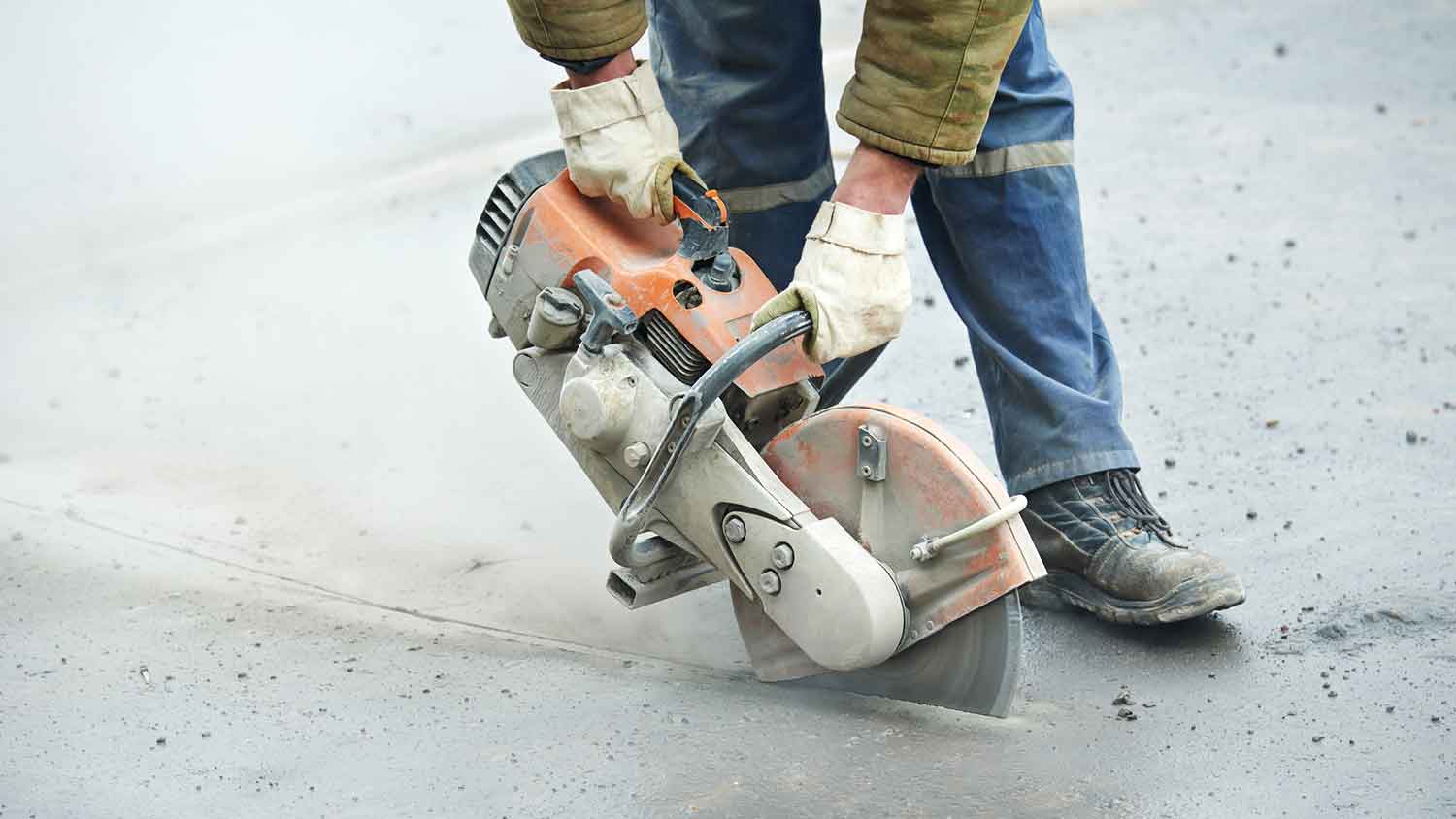 Worker using concrete saw to remove cement deck