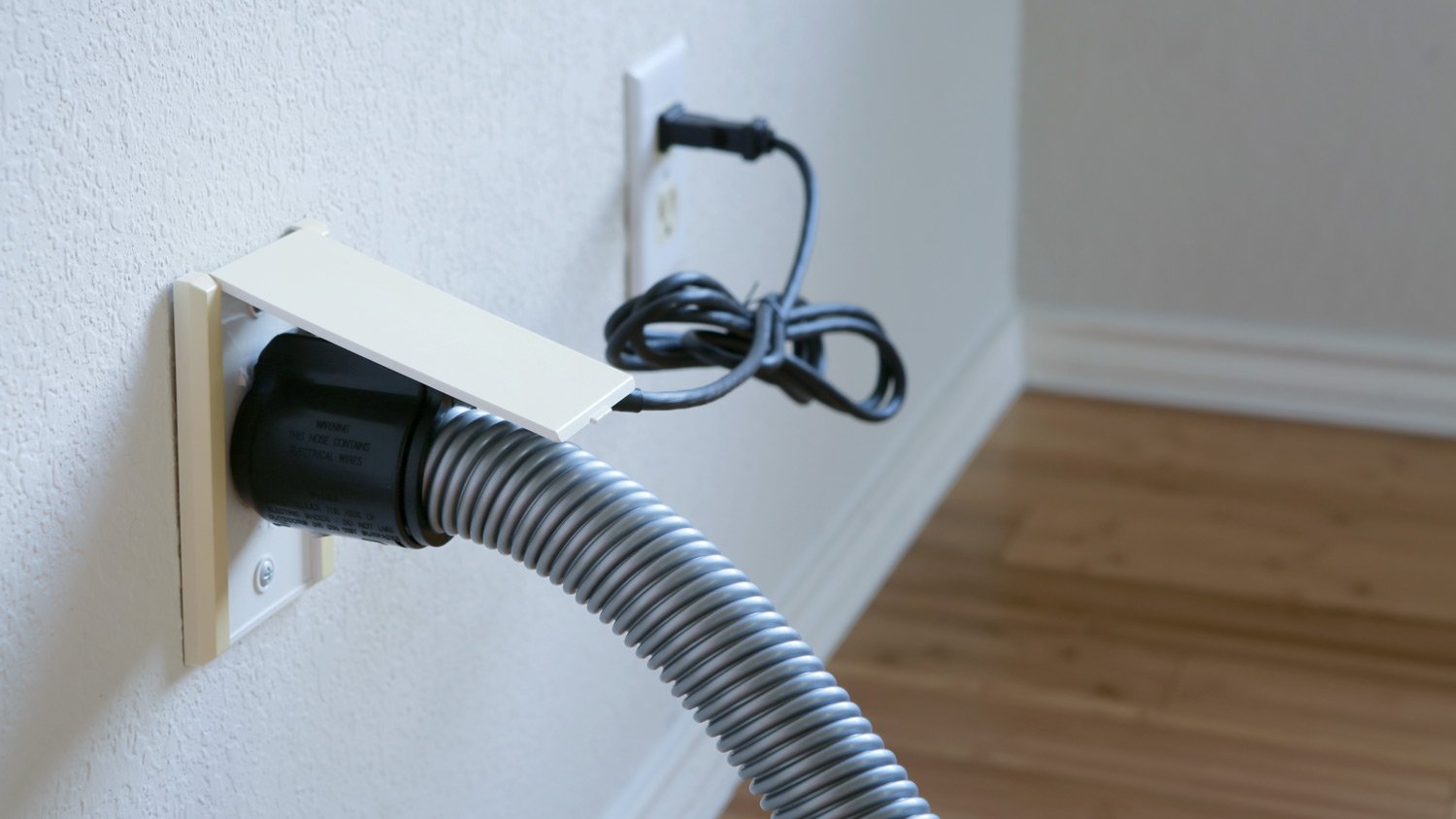 A central vacuum system hose connected to the wall