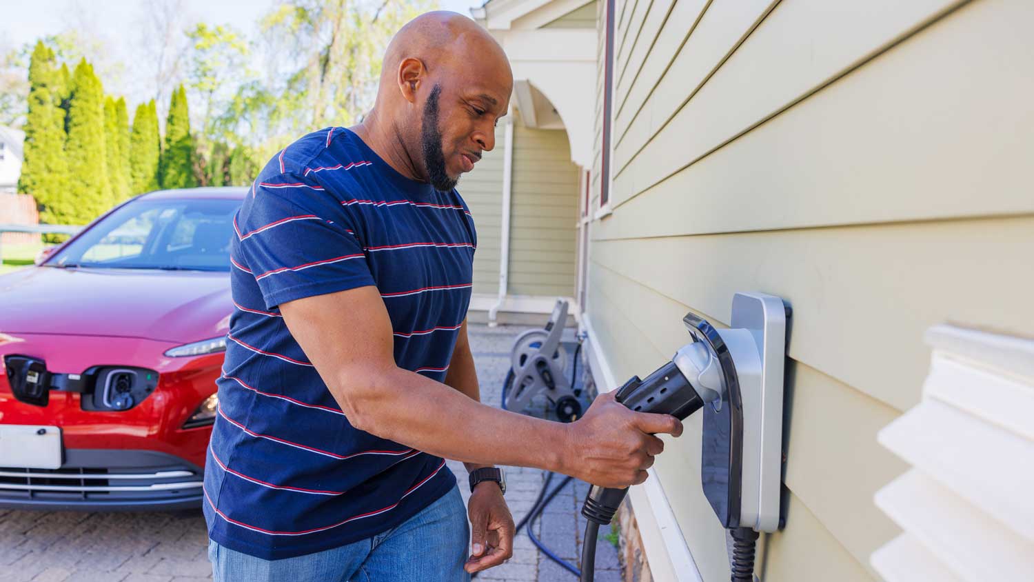 man charging his car in driveway 